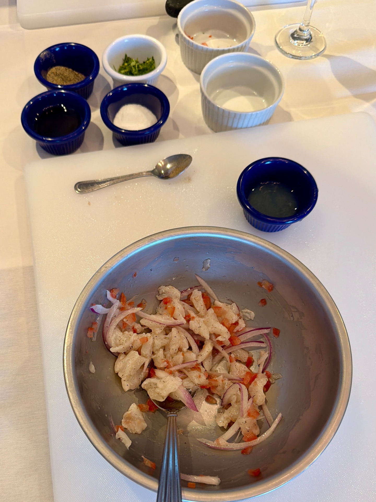 Cruise ship dining prep: bowl of marinated seafood with red onions and spices, surrounded by ingredient bowls and condiments.