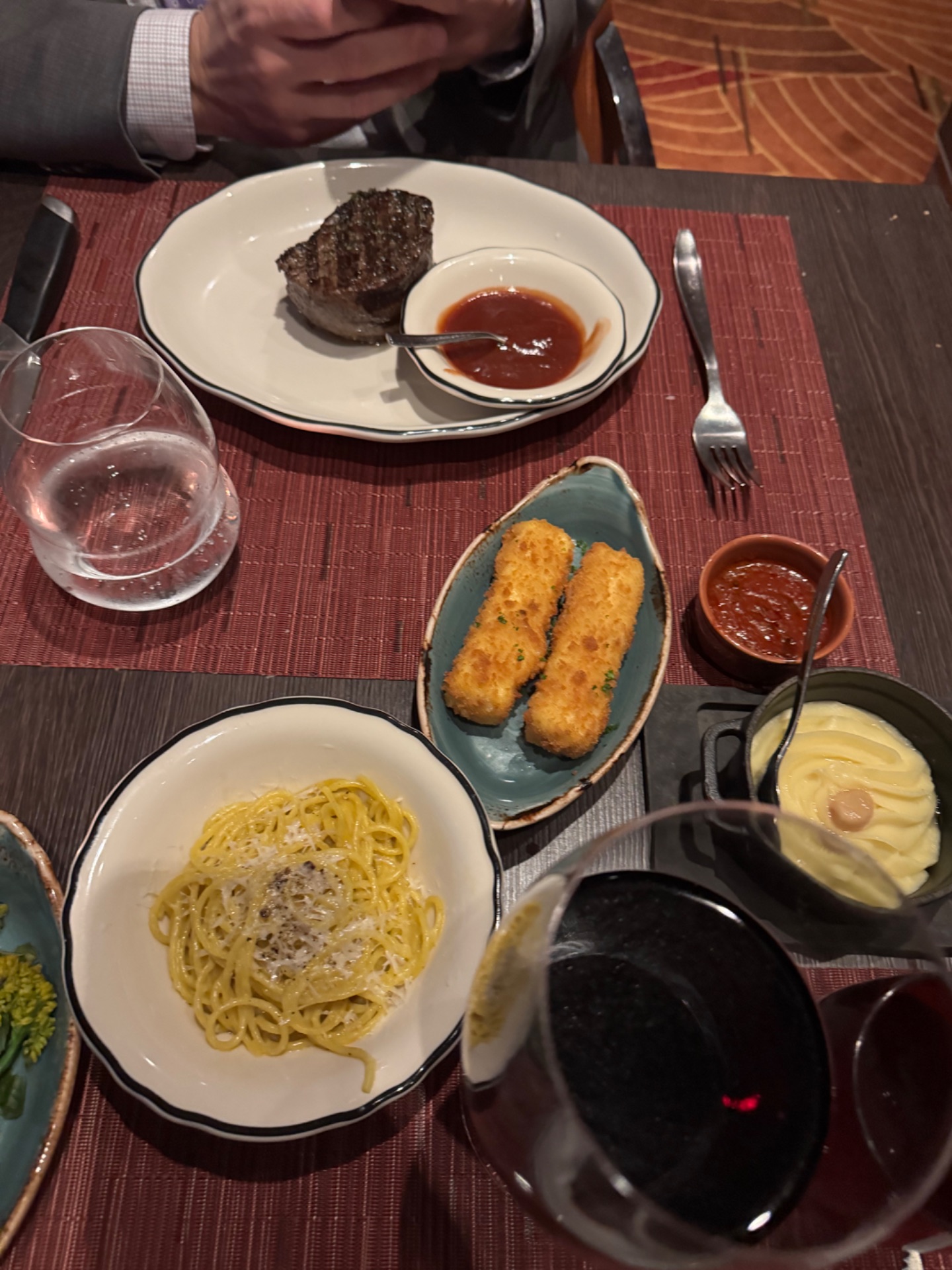 Fine dining table with steak, pasta, croquettes, and sauces at a formal restaurant dinner service.