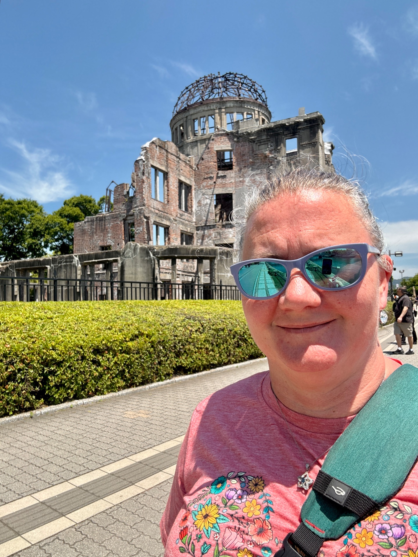 Tourist taking selfie at the Hiroshima Peace Memorial Genbaku Dome ruins on a sunny day.