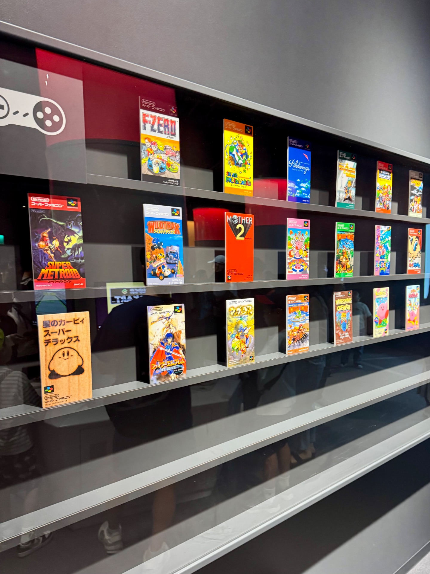 Display case of classic Nintendo Super Famicom game boxes and cartridges in a museum exhibit.