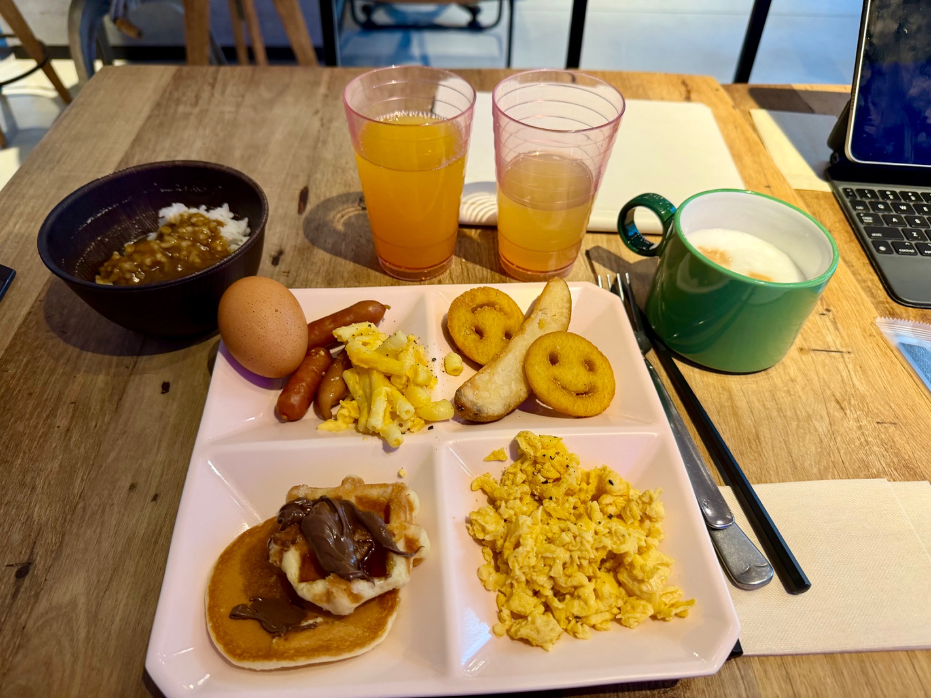 Breakfast plate with eggs, sausage, plantains, and toast, served with juice and milk on a cruise ship cabin table.