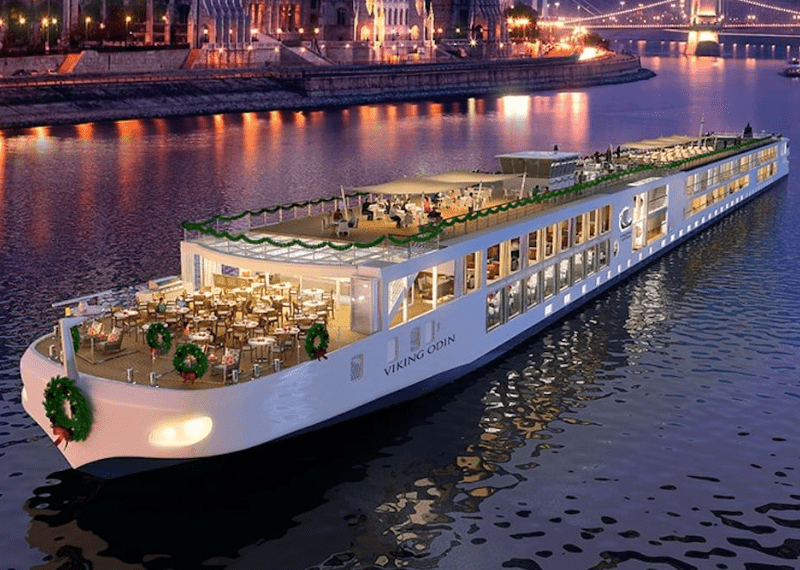 Viking Odin river cruise ship lit at dusk in Budapest with Parliament Building