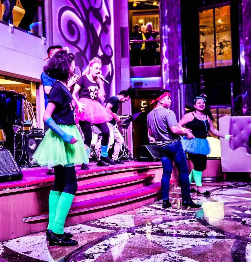 Colorful 80s-themed family dance party on cruise ship deck at night