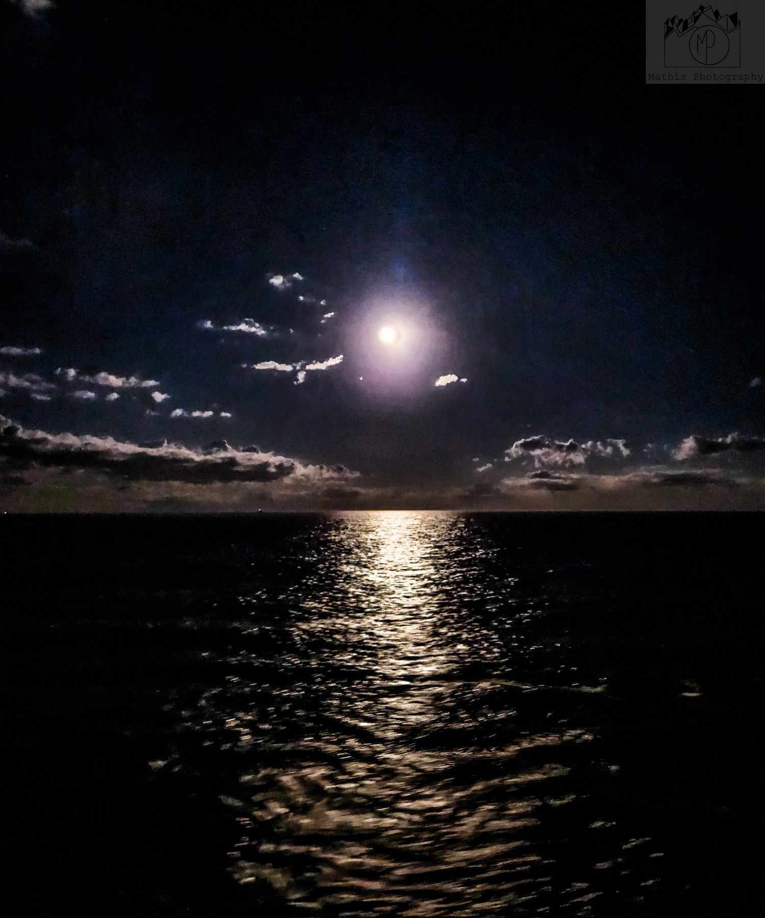 Moonlit ocean view with clouds and water reflection at night