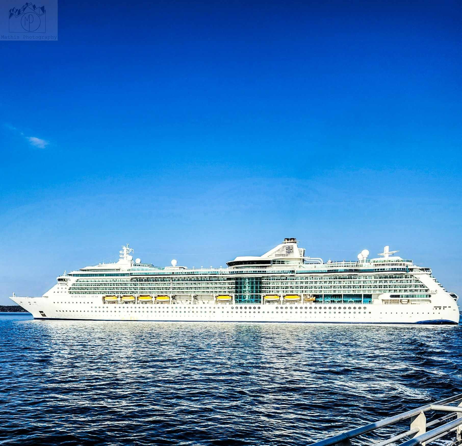 Large white cruise ship sailing on clear blue ocean water