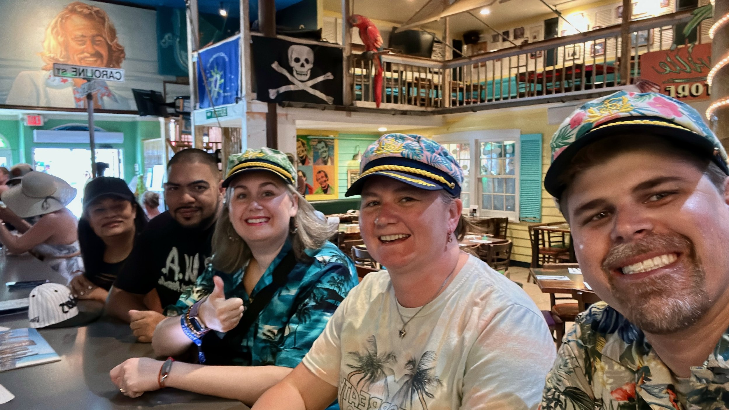 Group posing in pirate-themed cruise ship restaurant wearing captain hats