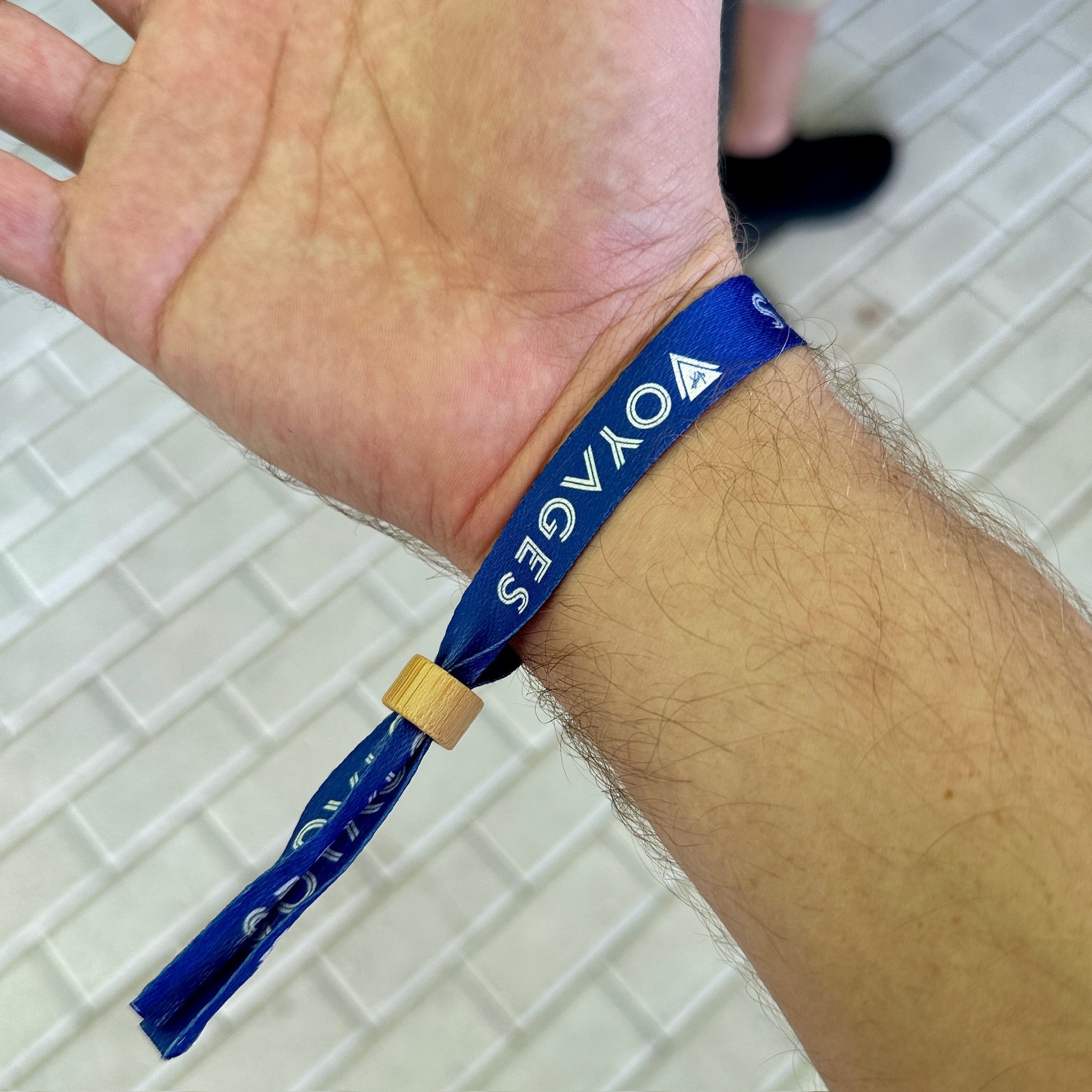 Person wearing blue cruise ship lanyard wristband with wooden bead