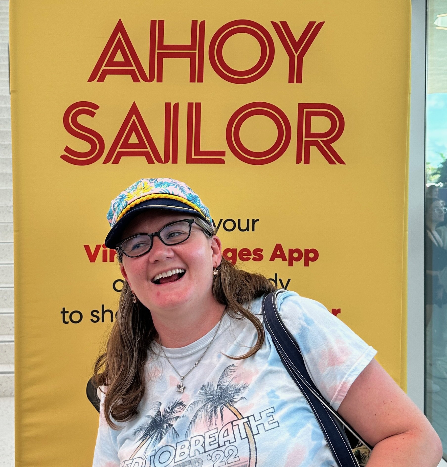 Woman posing in front of Ahoy Sailor cruise ship promotional banner