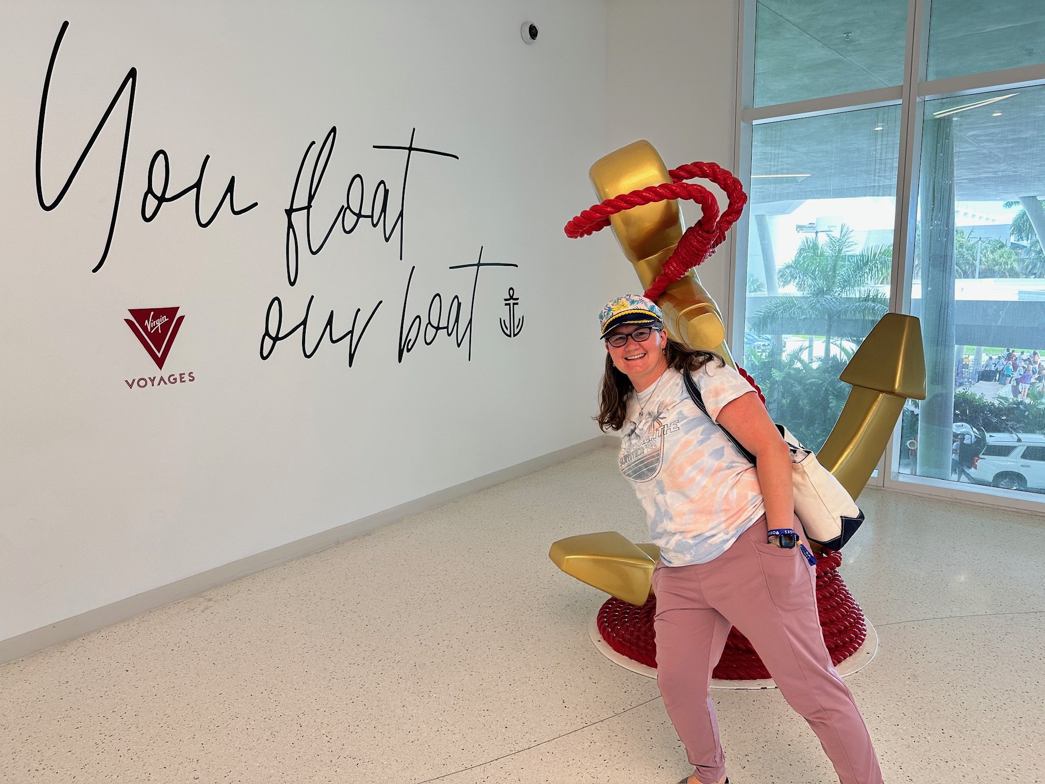 Woman poses with giant golden anchor statue Virgin Voyages