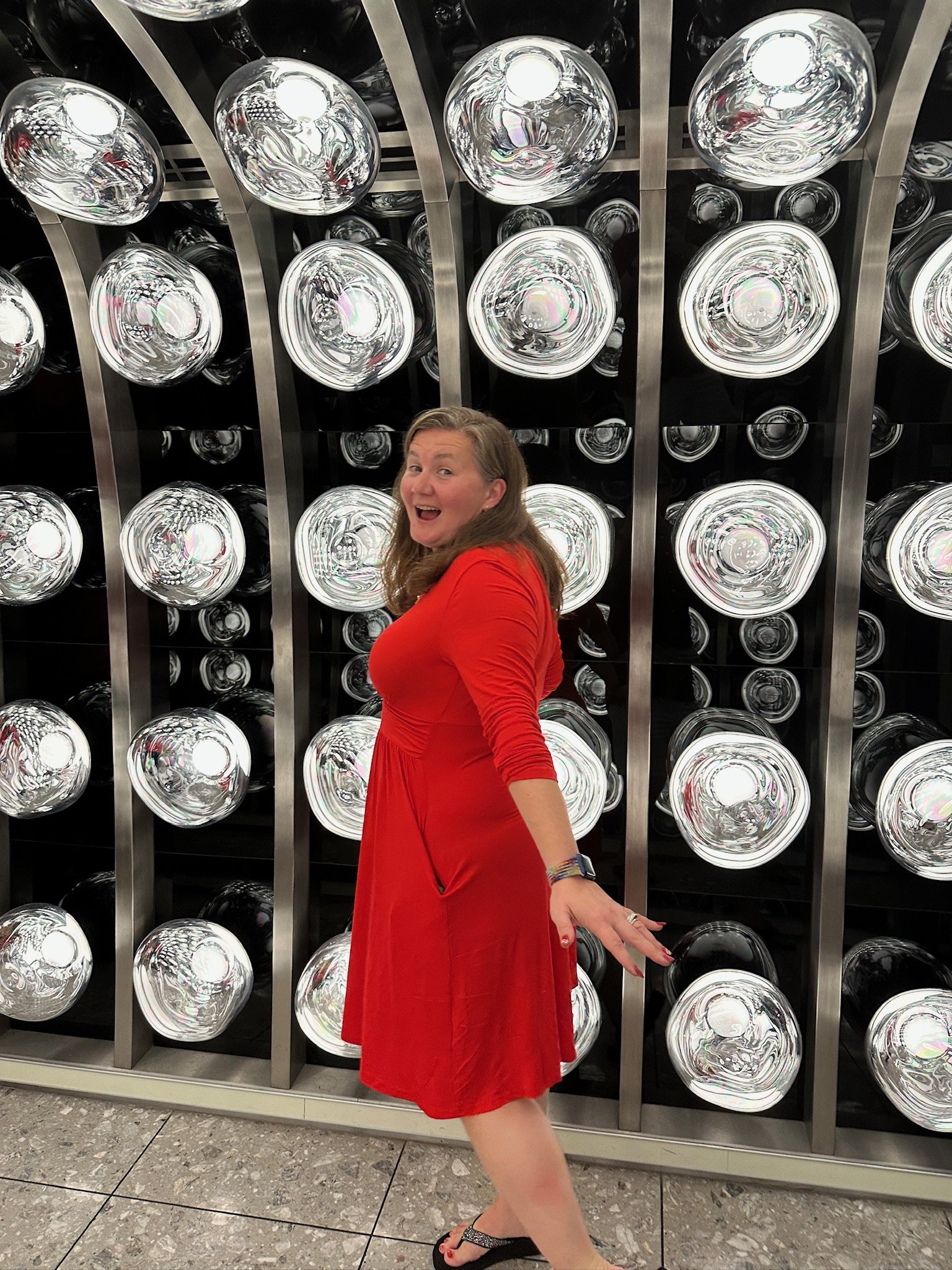 Woman in red dress poses before illuminated circular light display