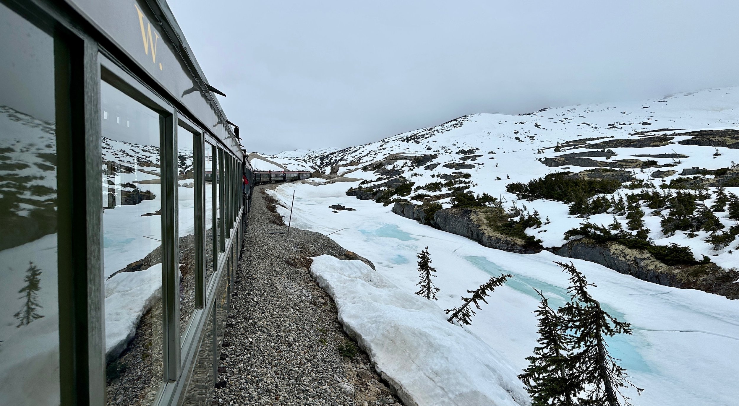 Modern building overlooks frozen turquoise lake in snowy alpine landscape