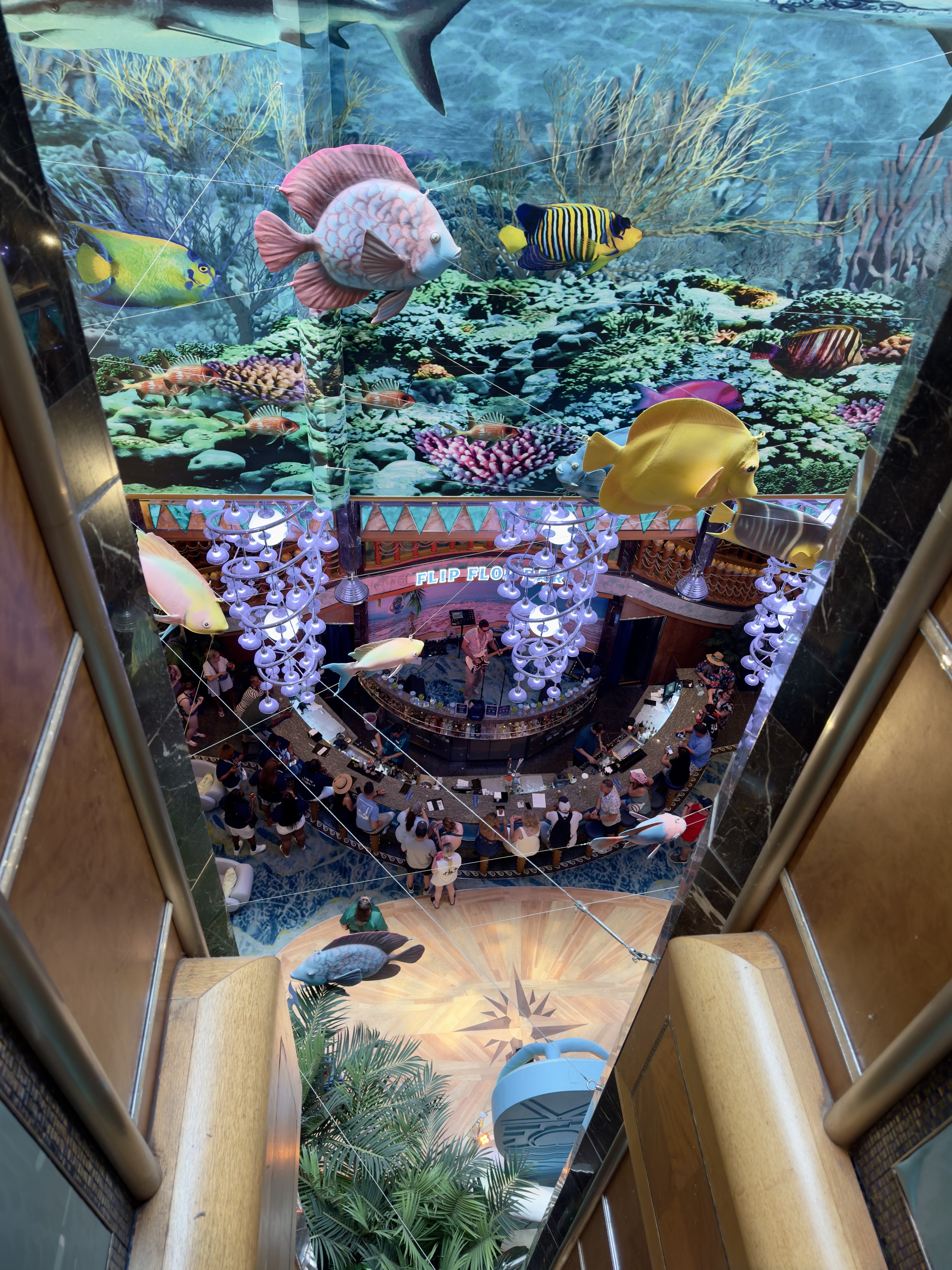 Cruise ship atrium with aquarium-themed entertainment and dining area