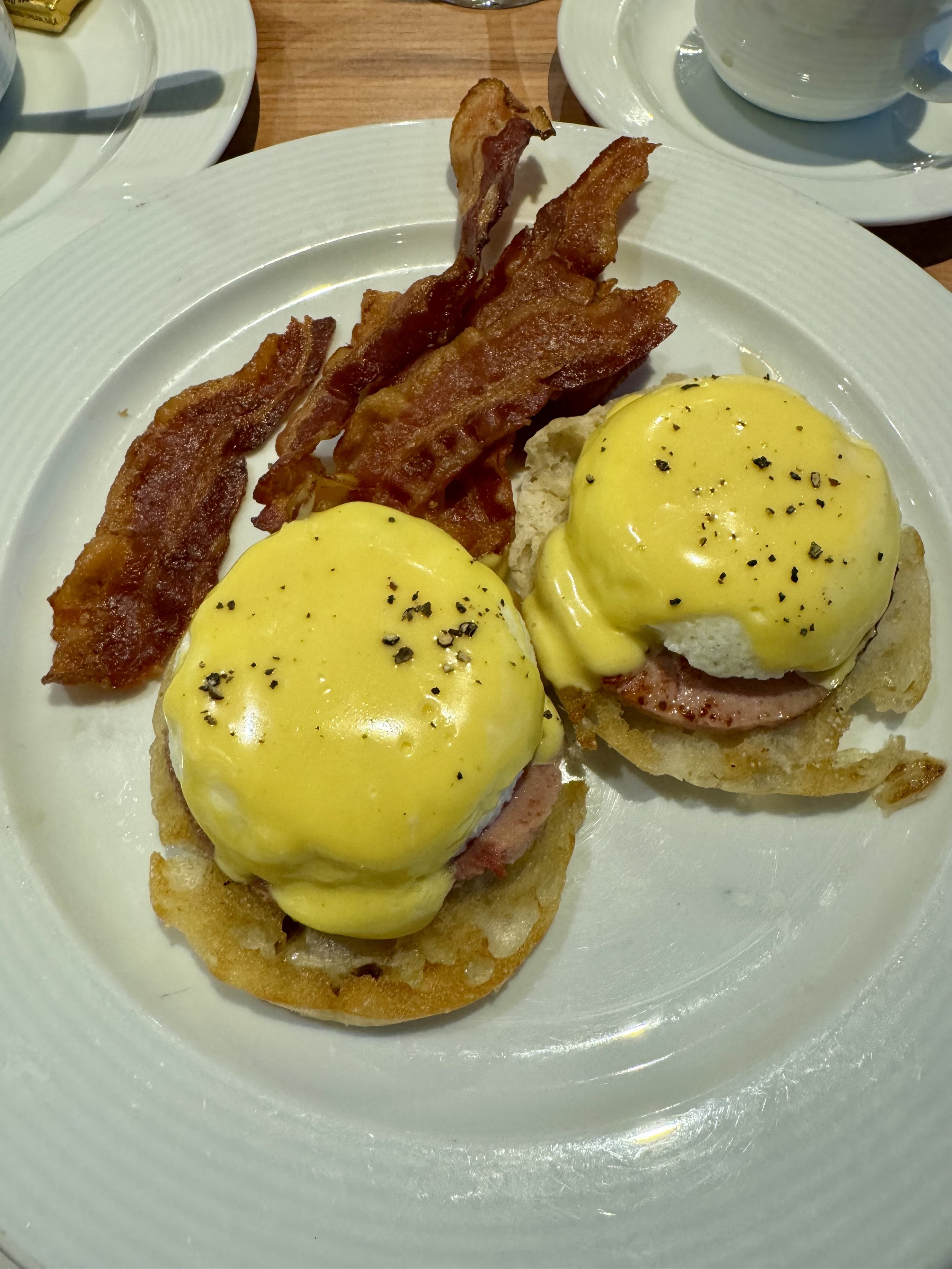 Eggs Benedict with bacon on white plate, cruise dining