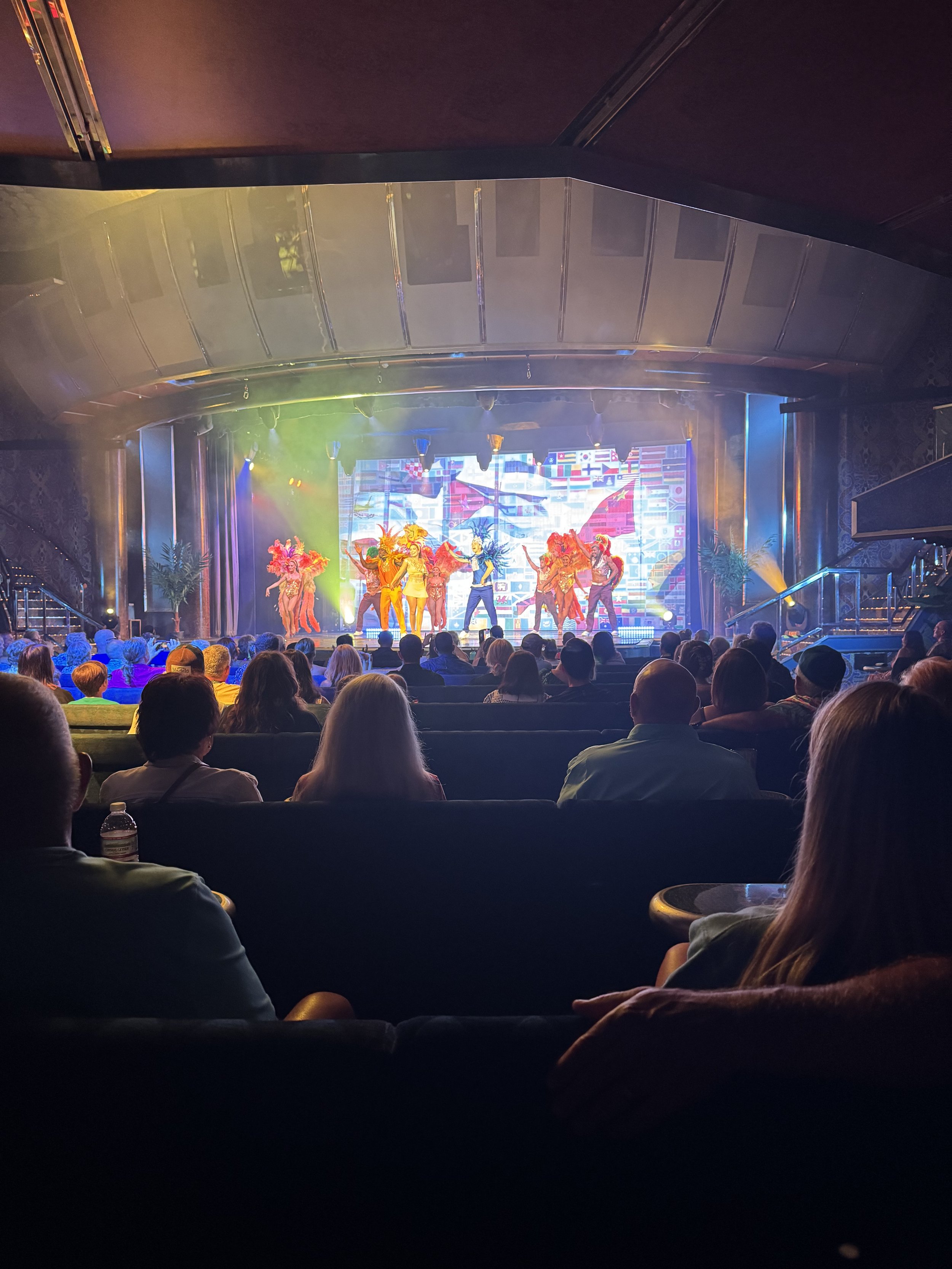 Cruise ship theater audience watching colorful costumed performers on stage