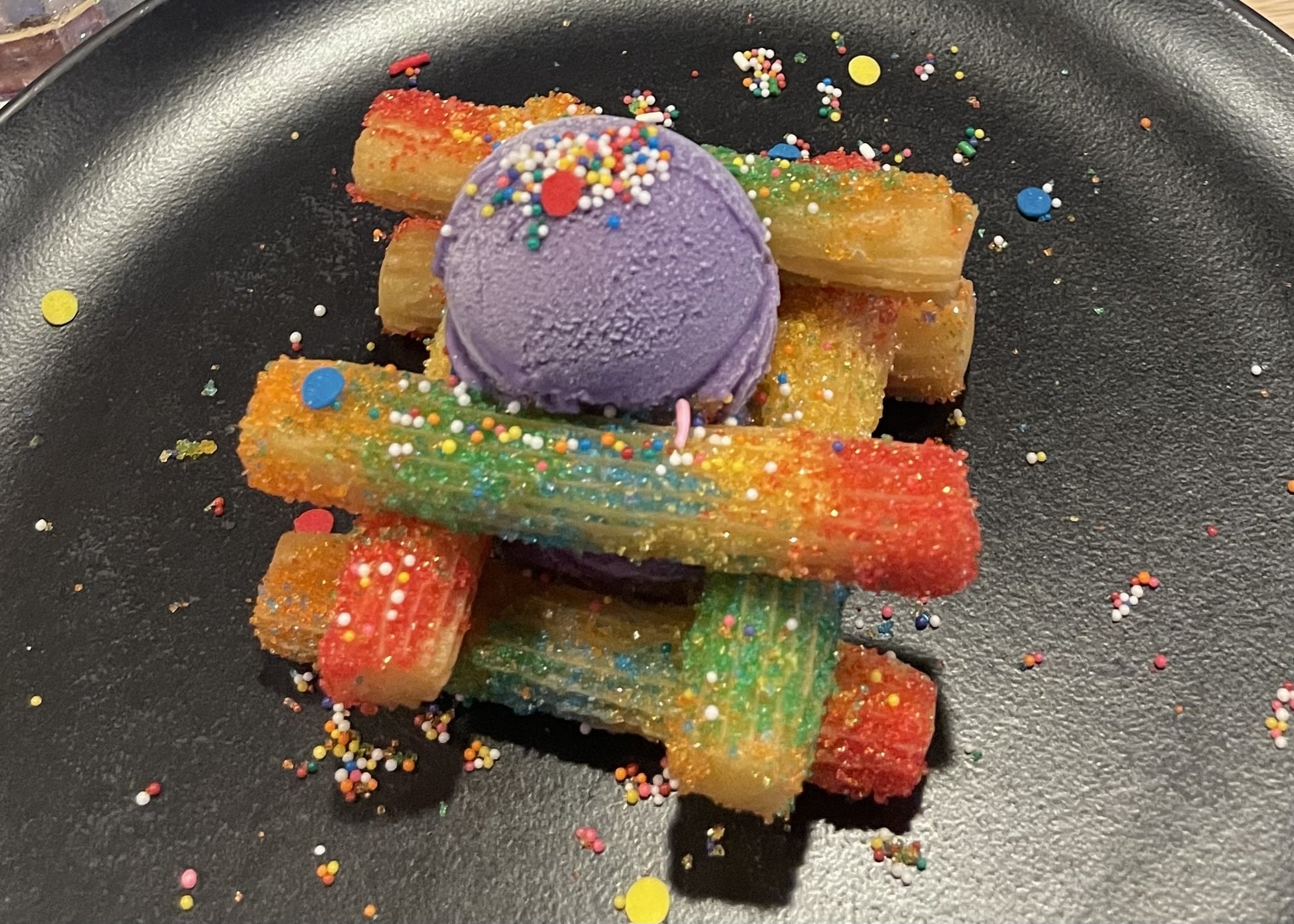Purple ice cream scoop on colorful sprinkled pastry sticks