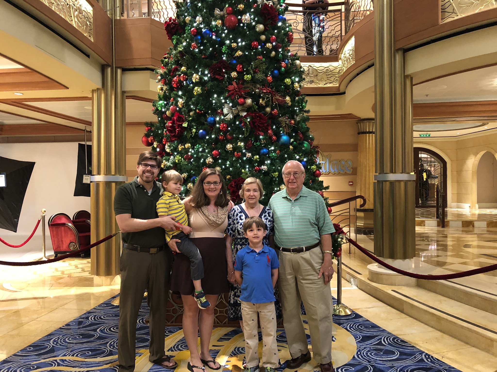 Family poses before decorated Christmas tree on cruise ship