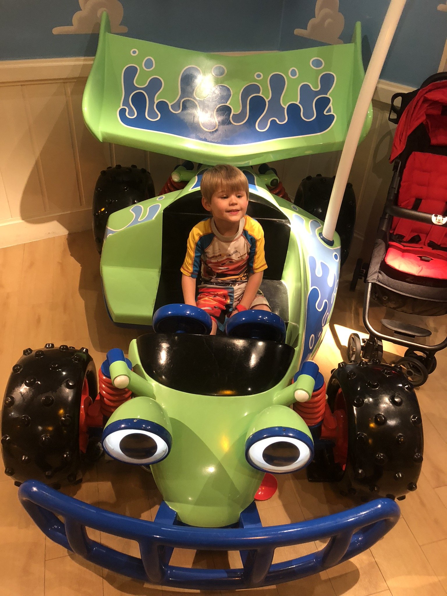 Young child riding green alien-themed amusement park ride