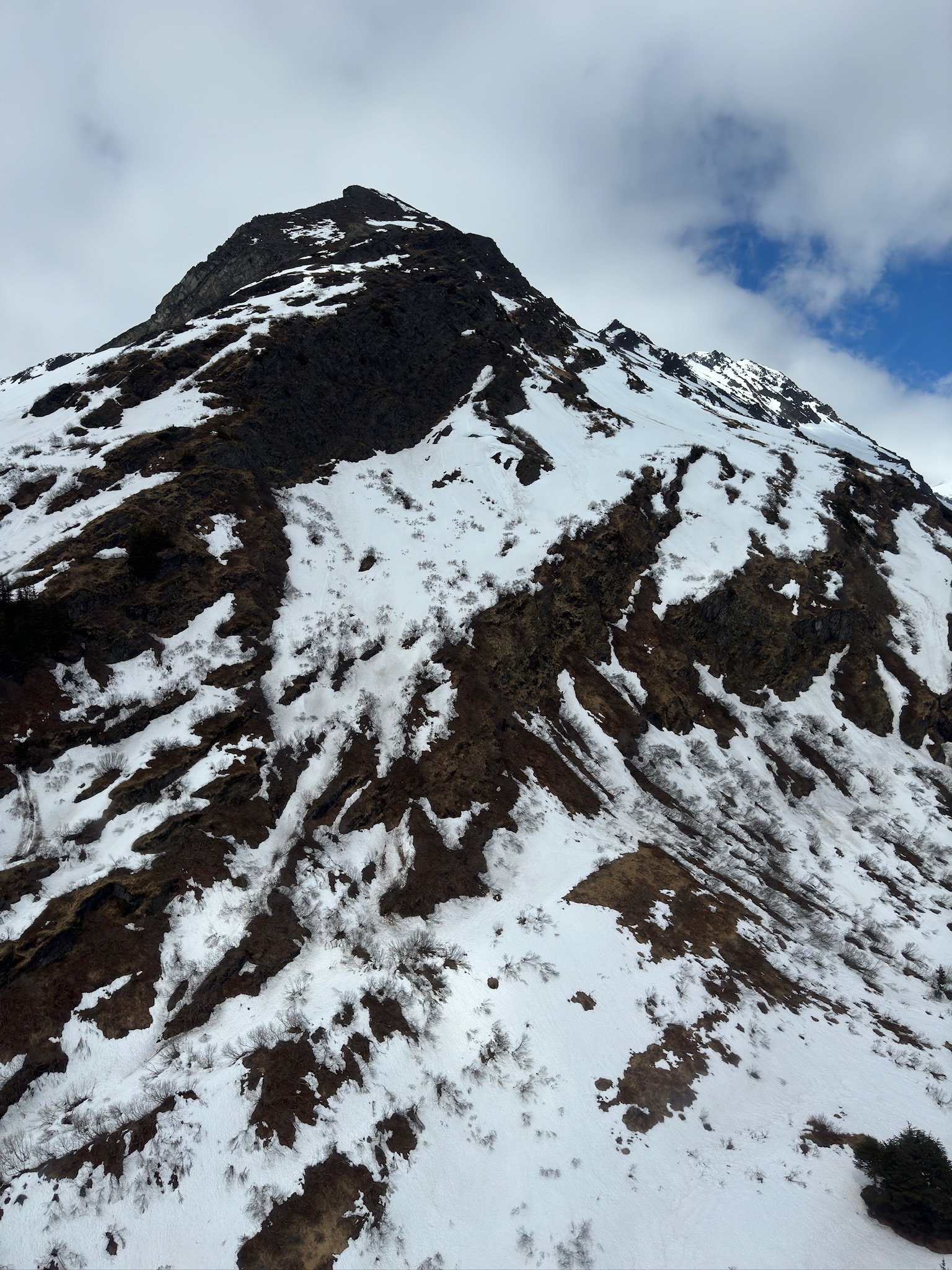 Snow-covered mountain peak with rocky terrain and sparse vegetation