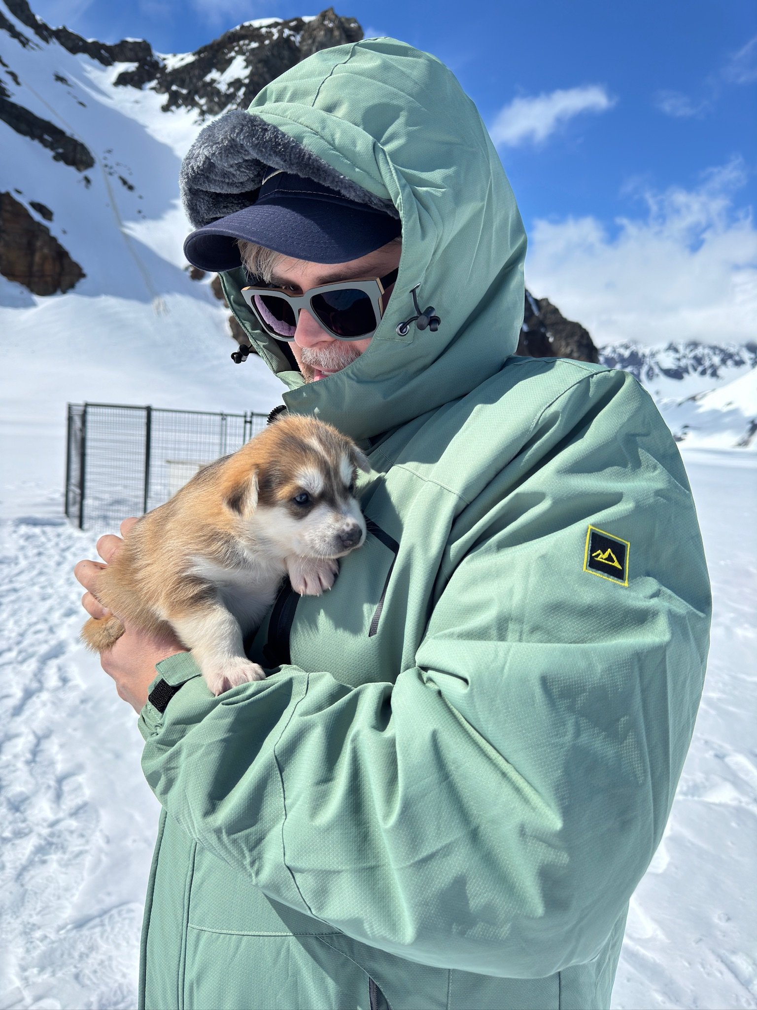 Man holding puppy in snowy mountain landscape