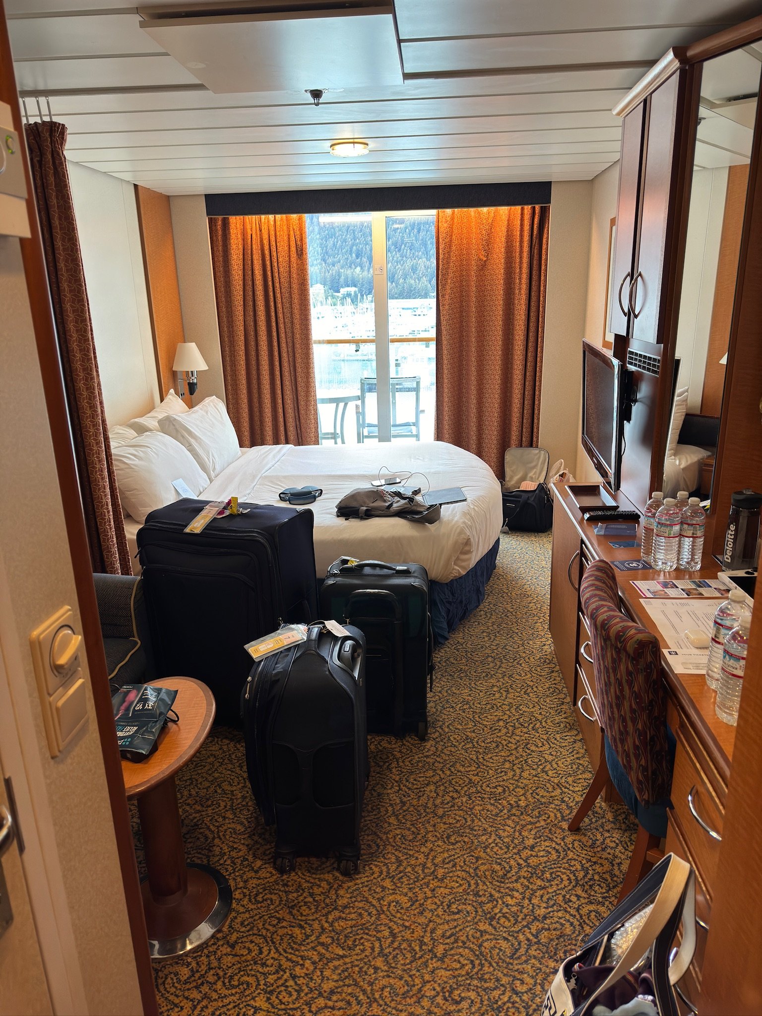 Cruise ship cabin with balcony view of snowy mountains and forest