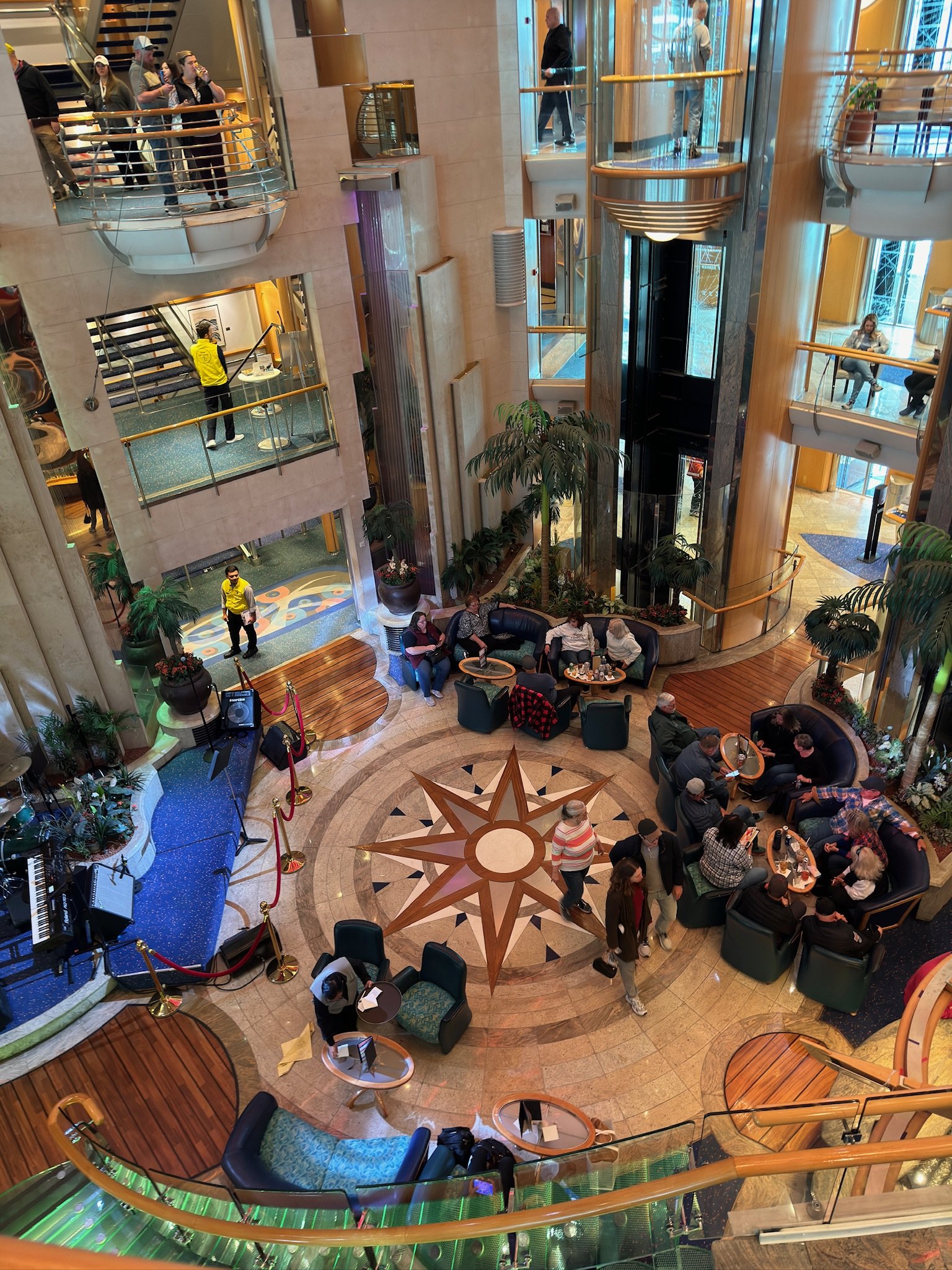 Multi-deck atrium with star compass floor and passengers gathered below