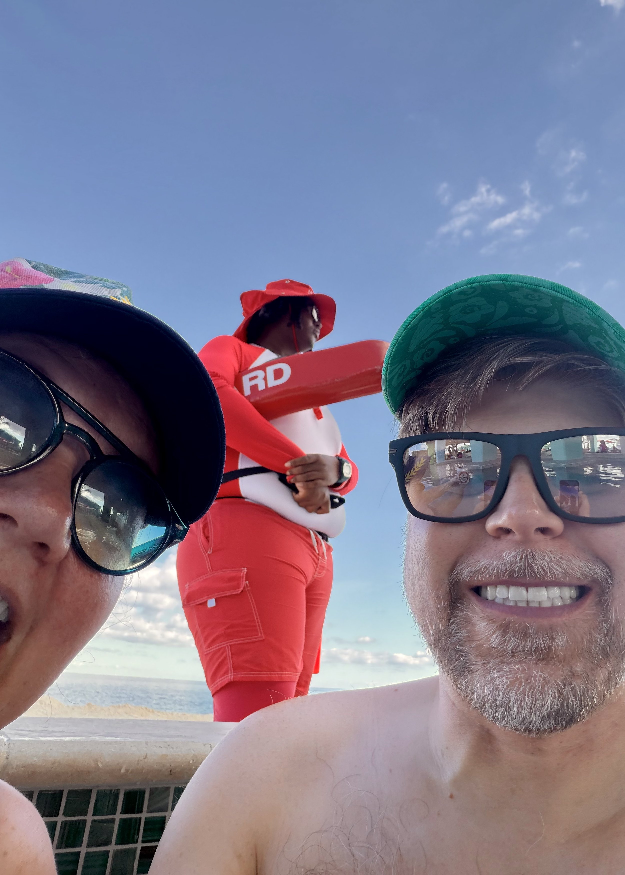 Three men on cruise ship deck with lifeguard statue