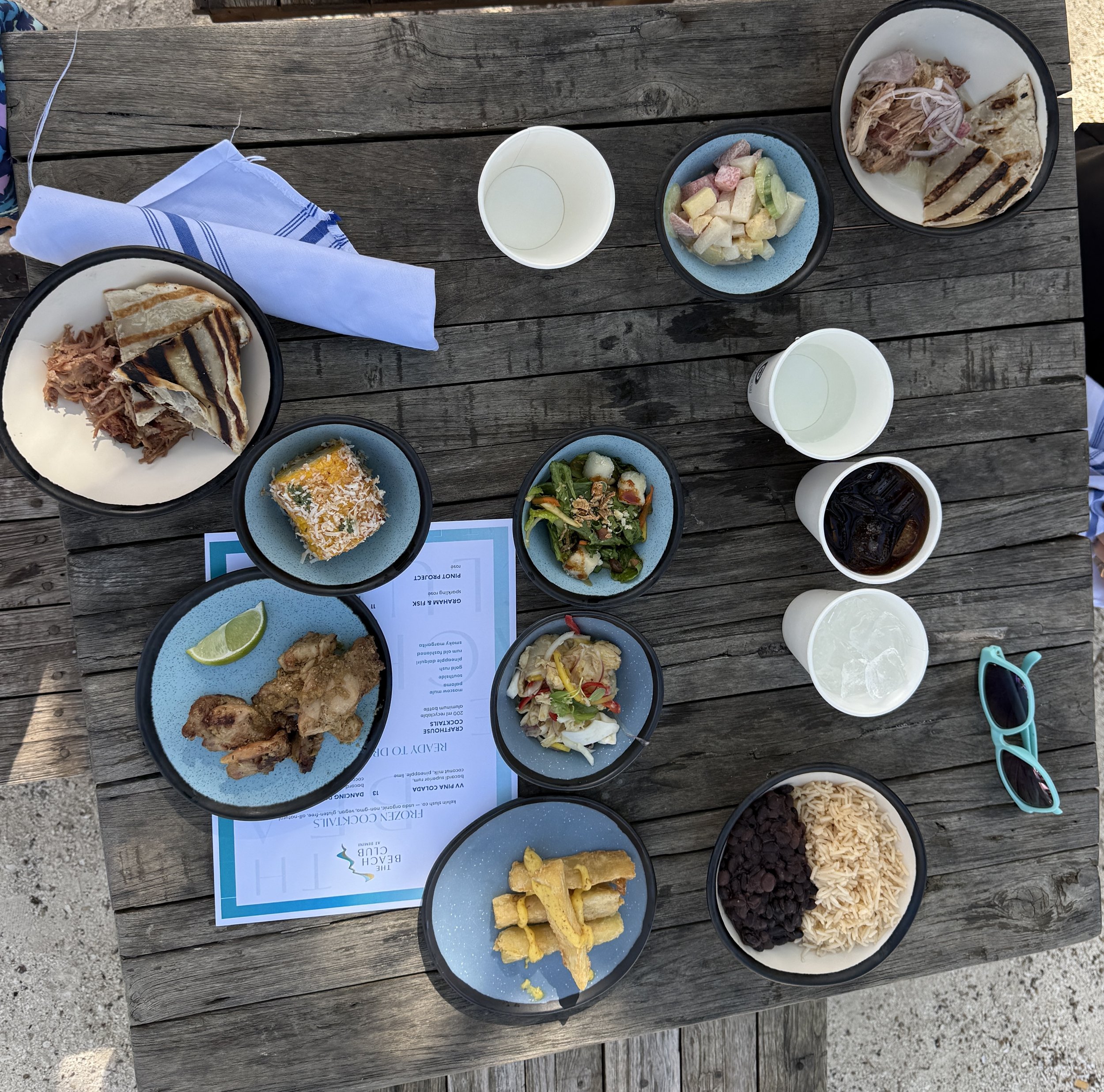 Seafood platter spread with grilled fish, fries, rice, and fresh vegetables on wooden deck table