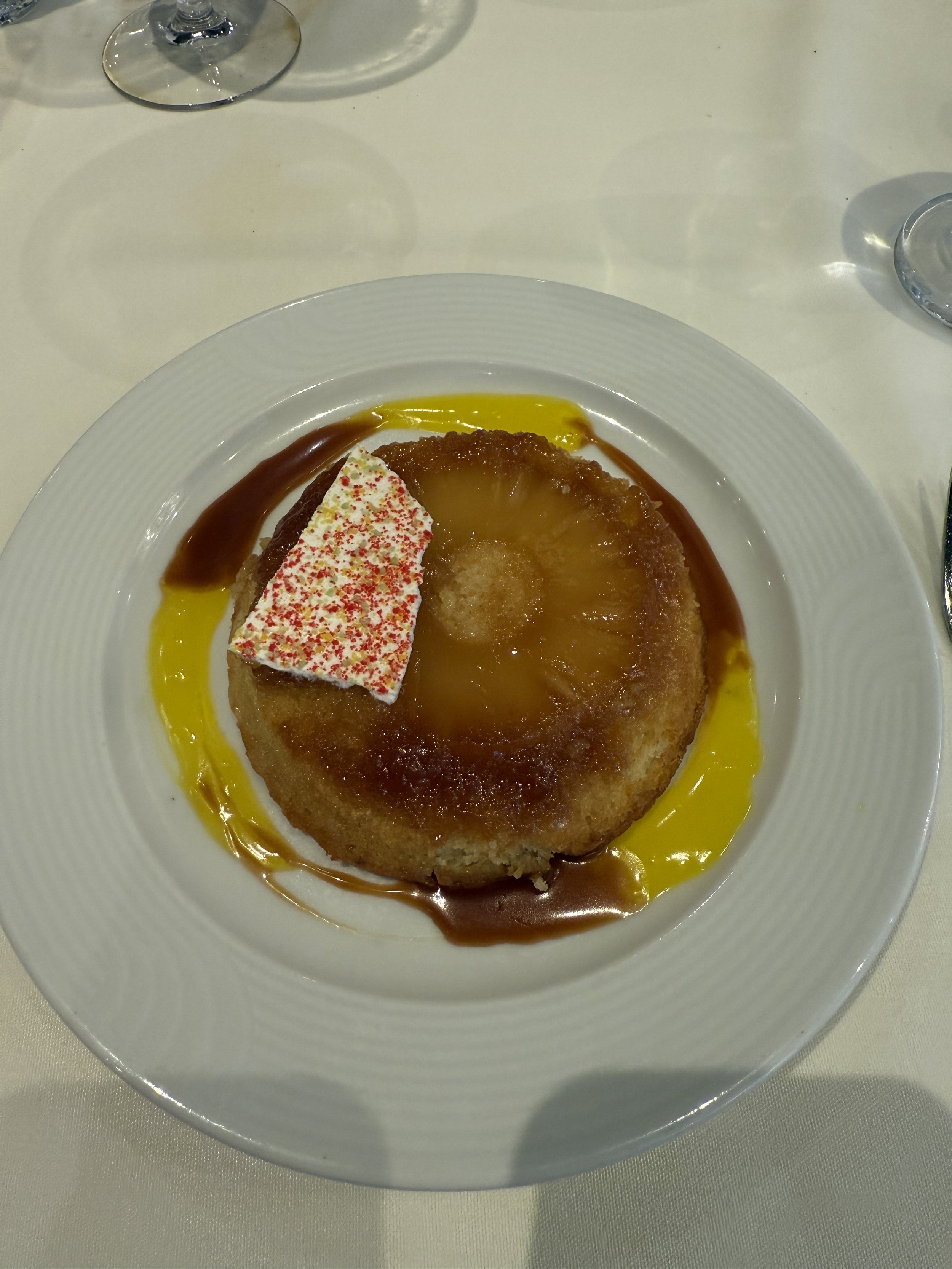 Gourmet plated dessert with caramel sauce and red-white candy garnish