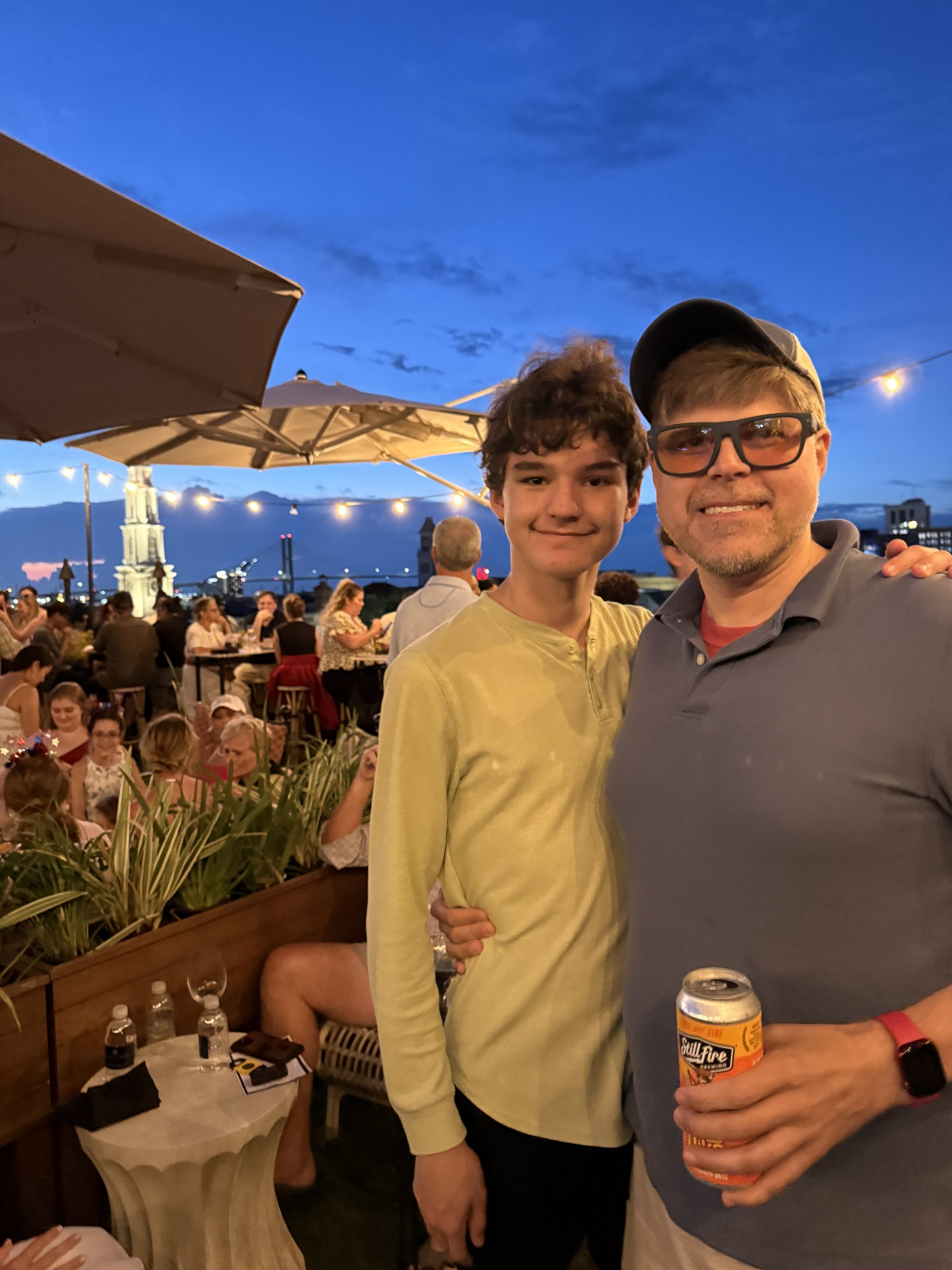 Two men enjoying rooftop bar at dusk with mountain views