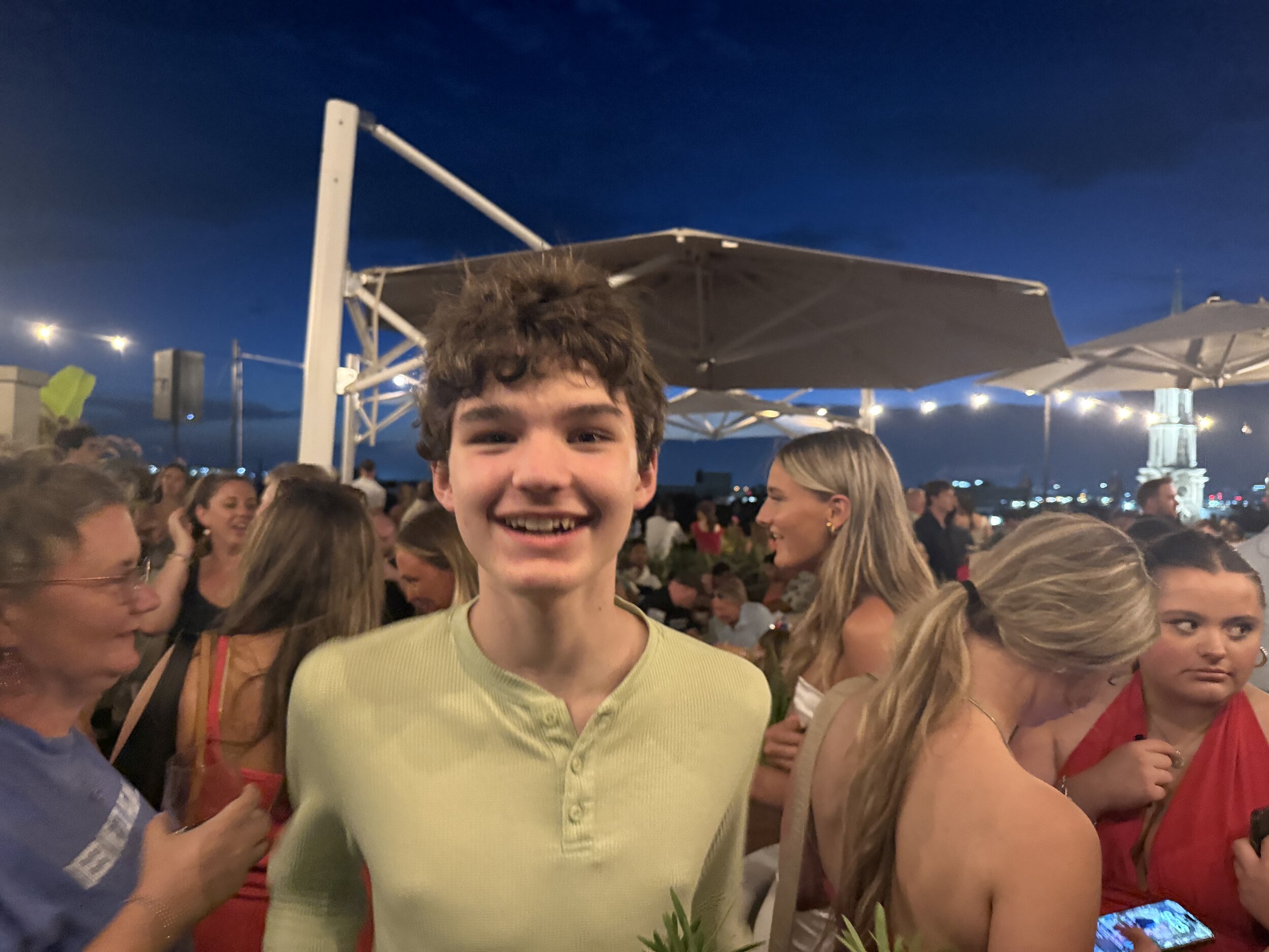 Young boy smiling at evening outdoor deck party with umbrella shade