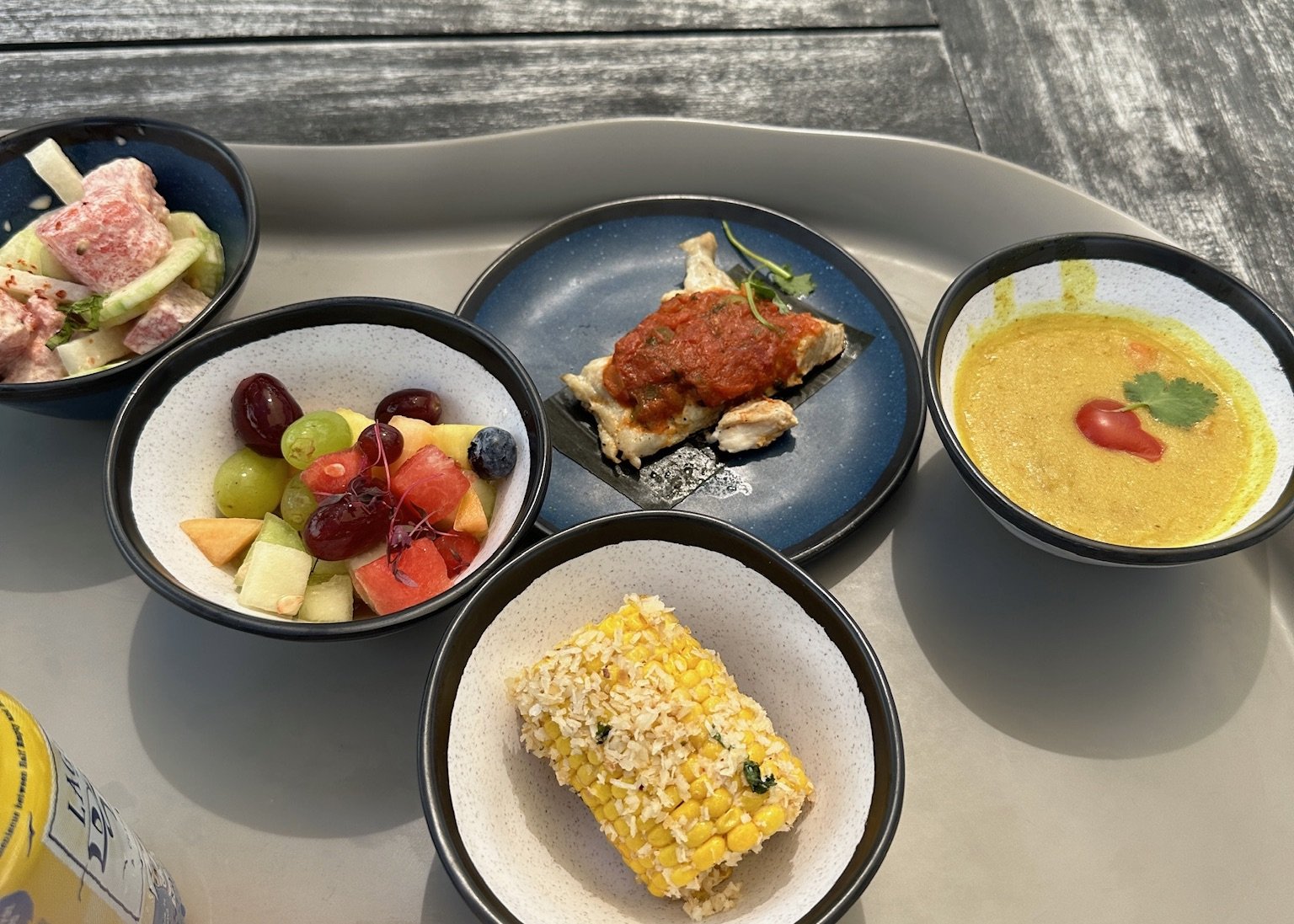 Gourmet tasting platter with corn, fruit, soup, and seafood appetizers