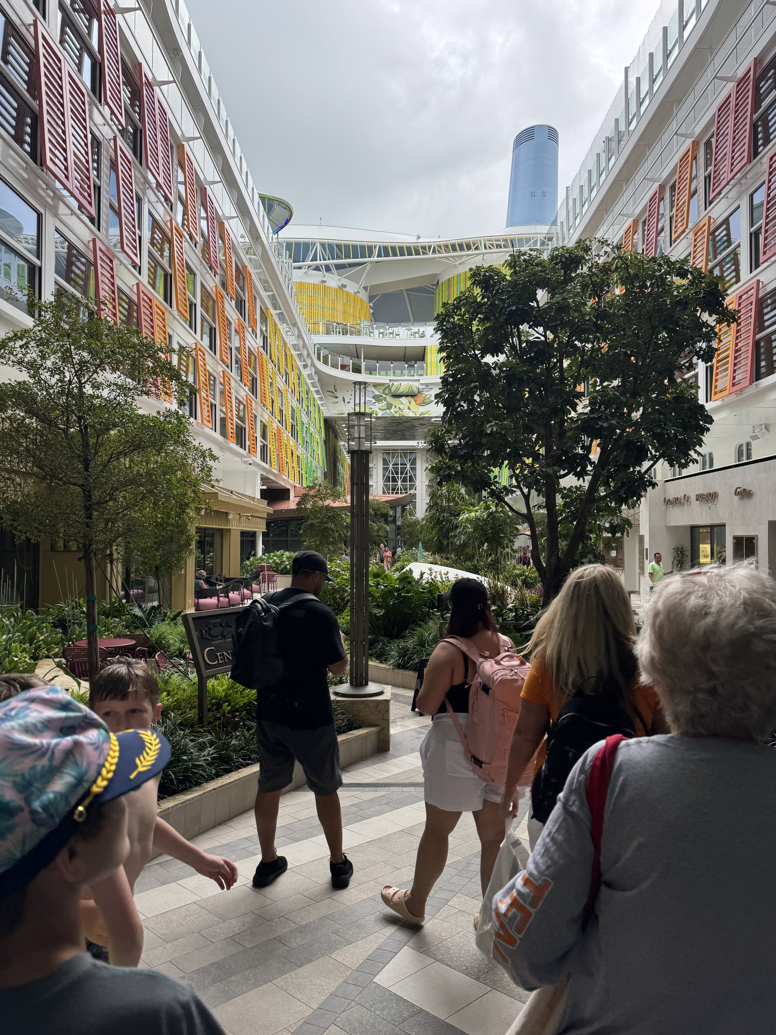 Modern cruise ship courtyard with colorful residential-style buildings and greenery