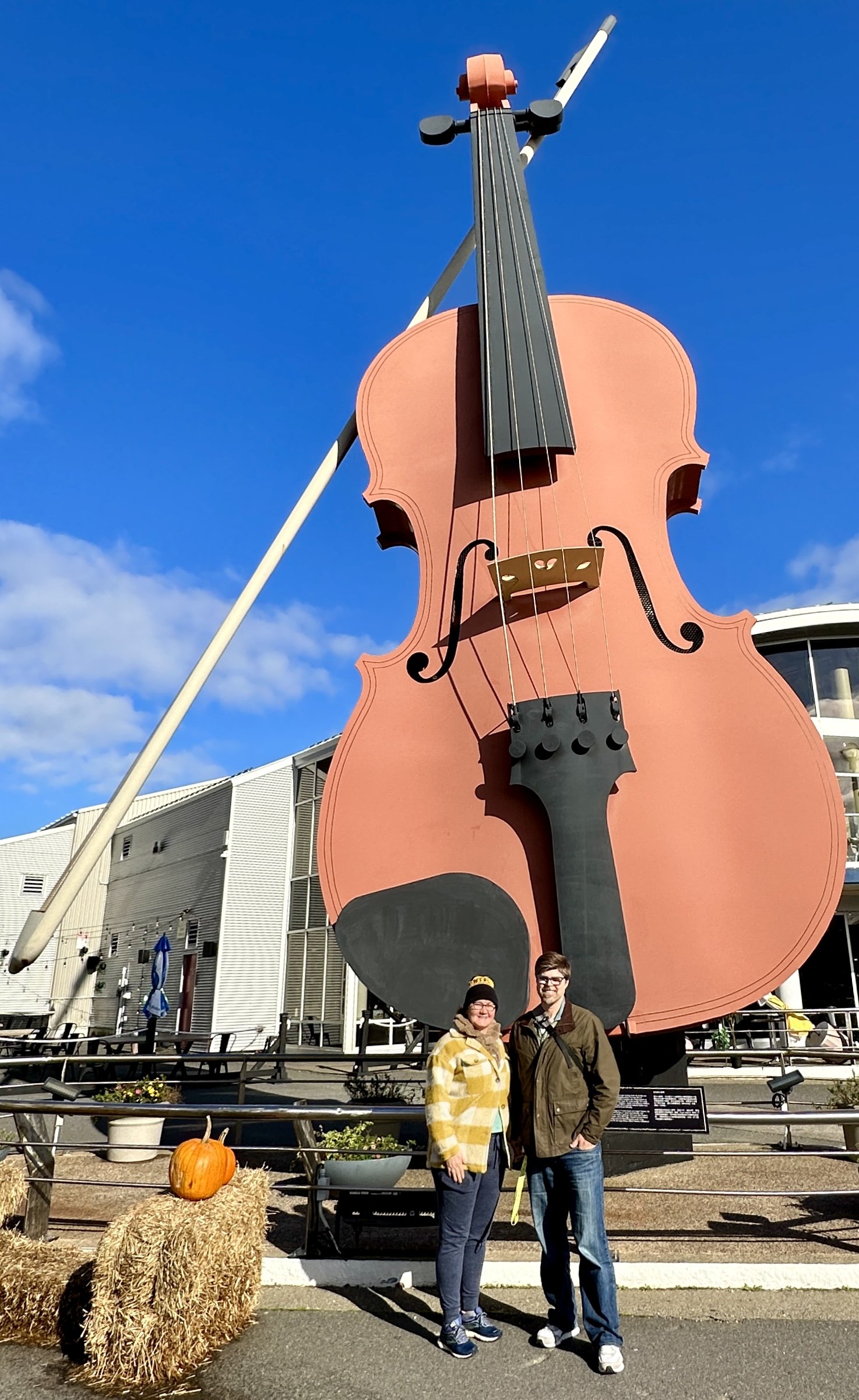 Giant pink violin sculpture with two visitors posing below