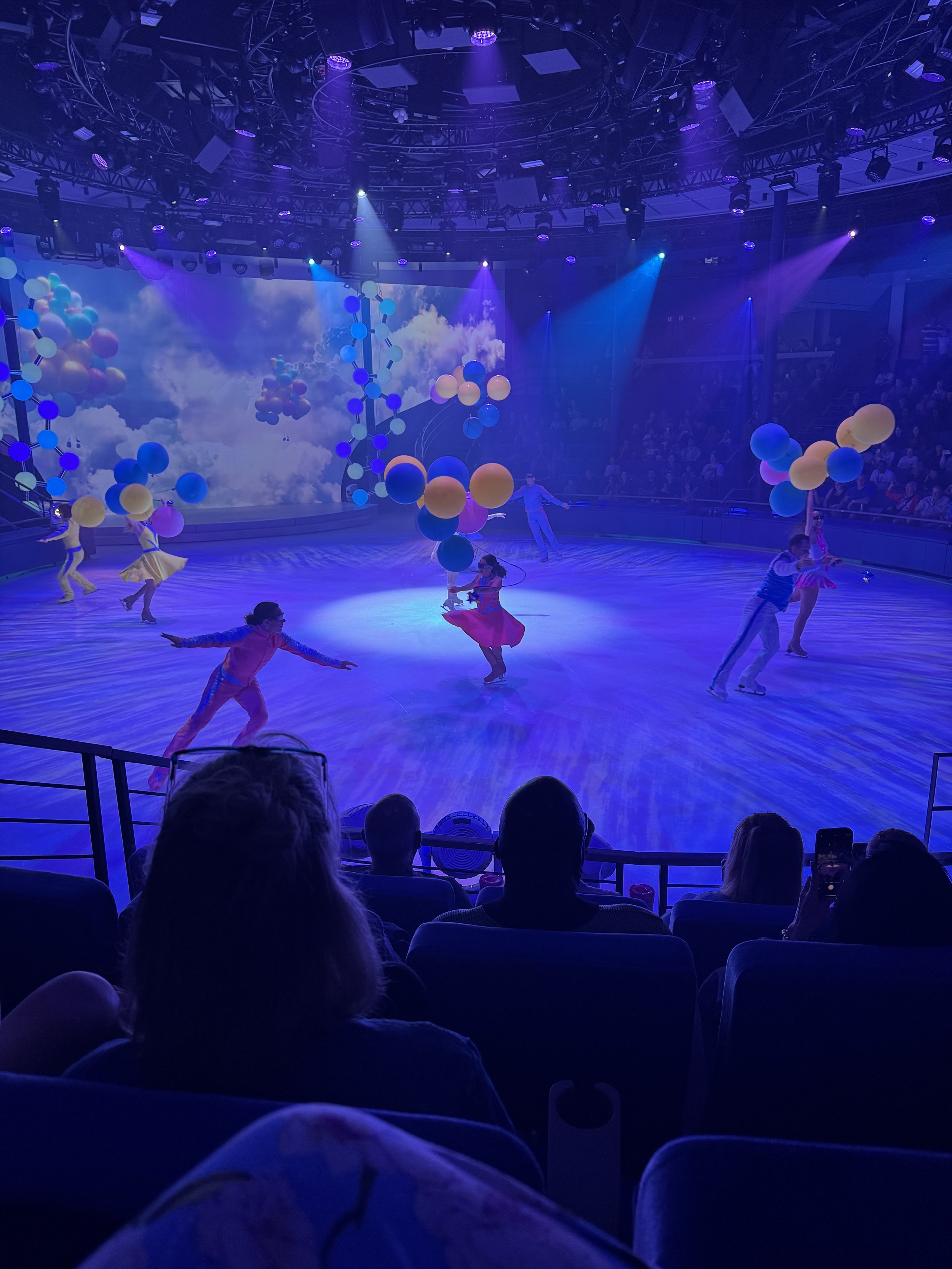 Circus acrobats performing with colorful balloons under blue stage lights