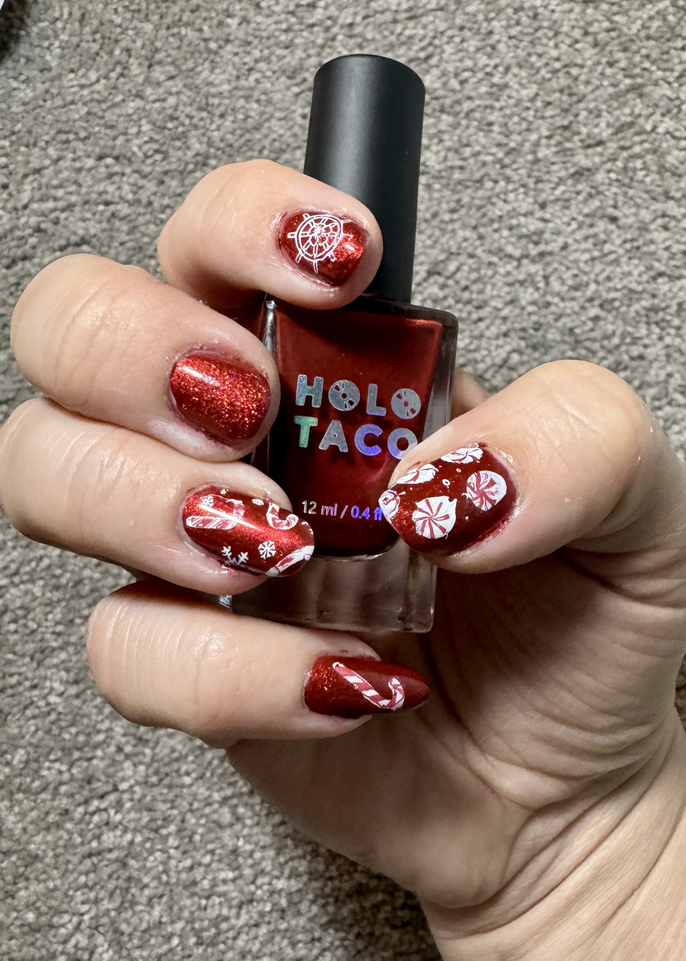 Red glitter nails with holiday designs and Holo Taco polish bottle