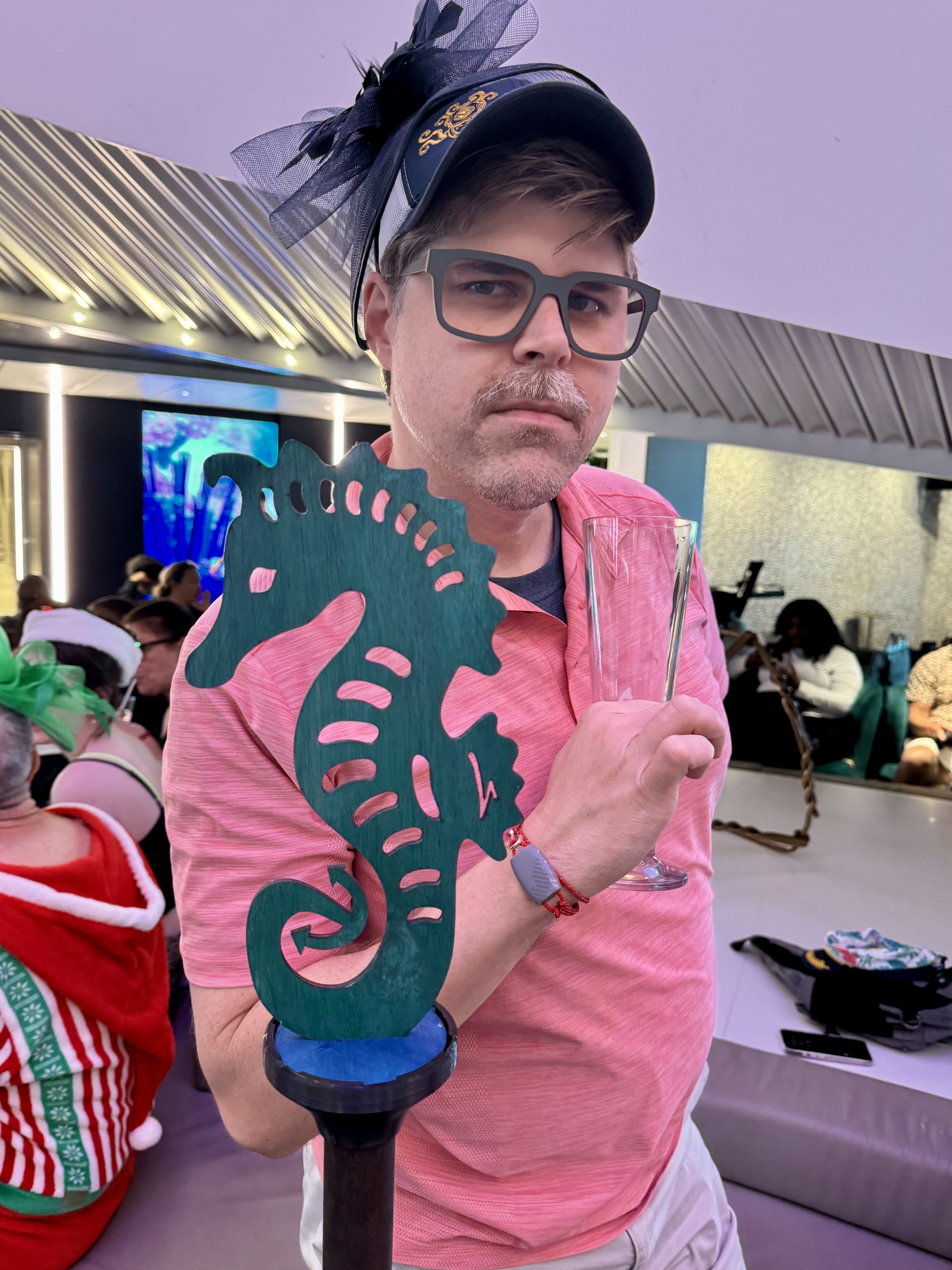 Man displays handcrafted teal seahorse sculpture at cruise event