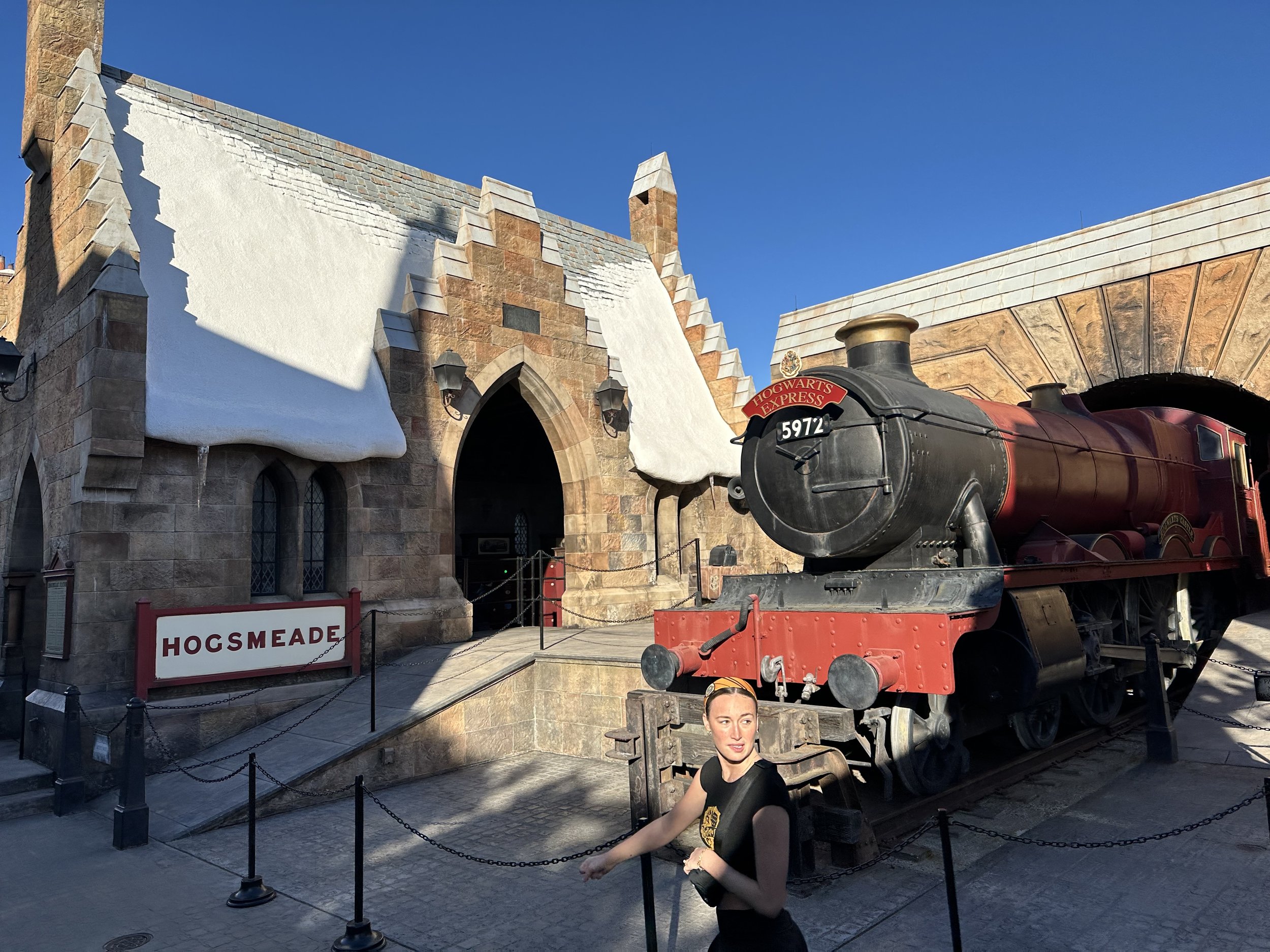 Visitor poses with Hogwarts Express train at theme park