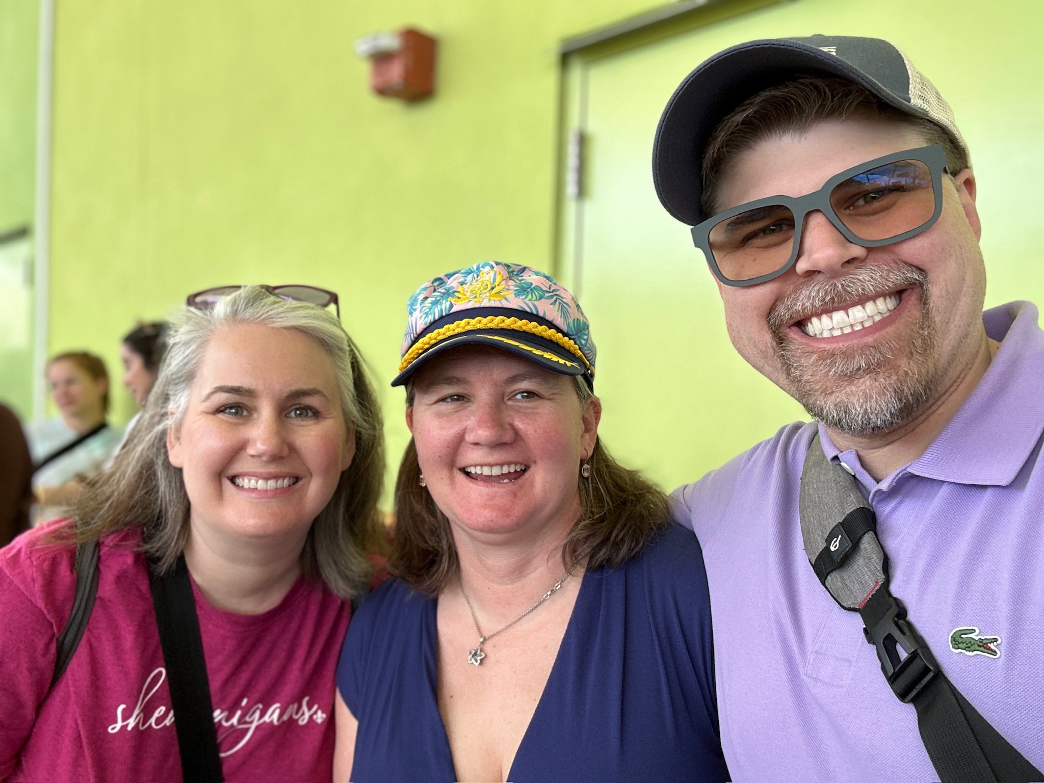 Three smiling friends at indoor venue with lime green walls