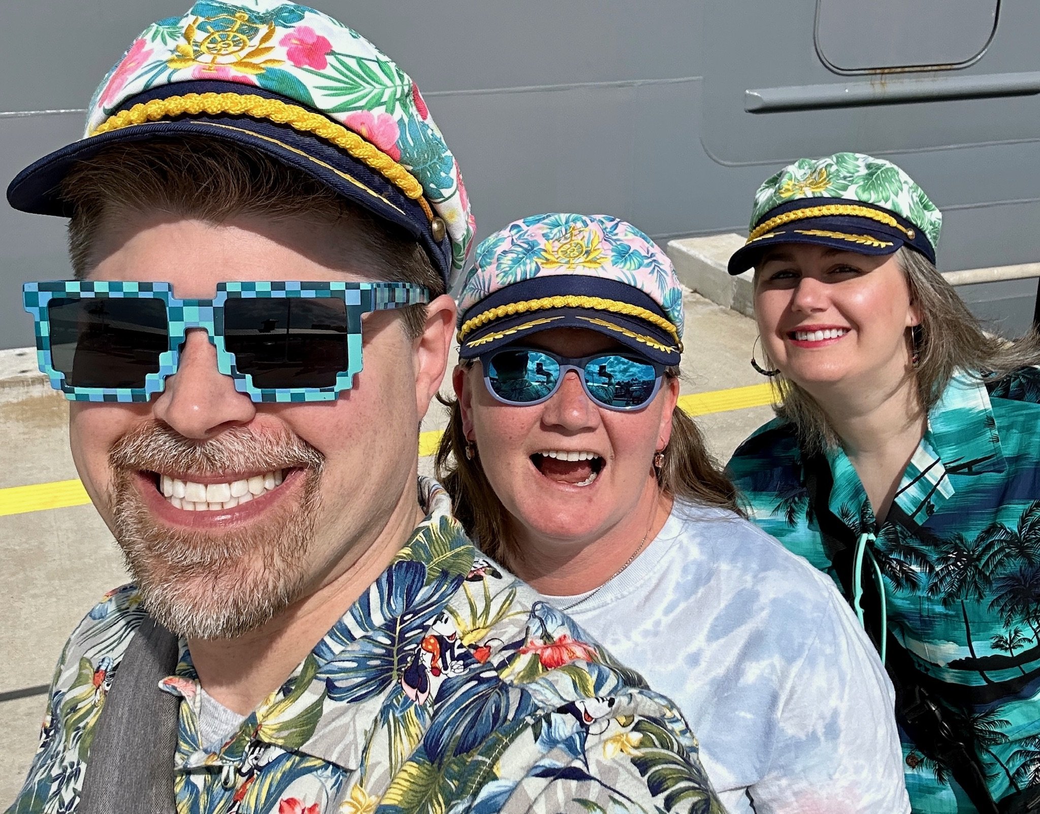 Three people in tropical cruise wear and nautical captain hats