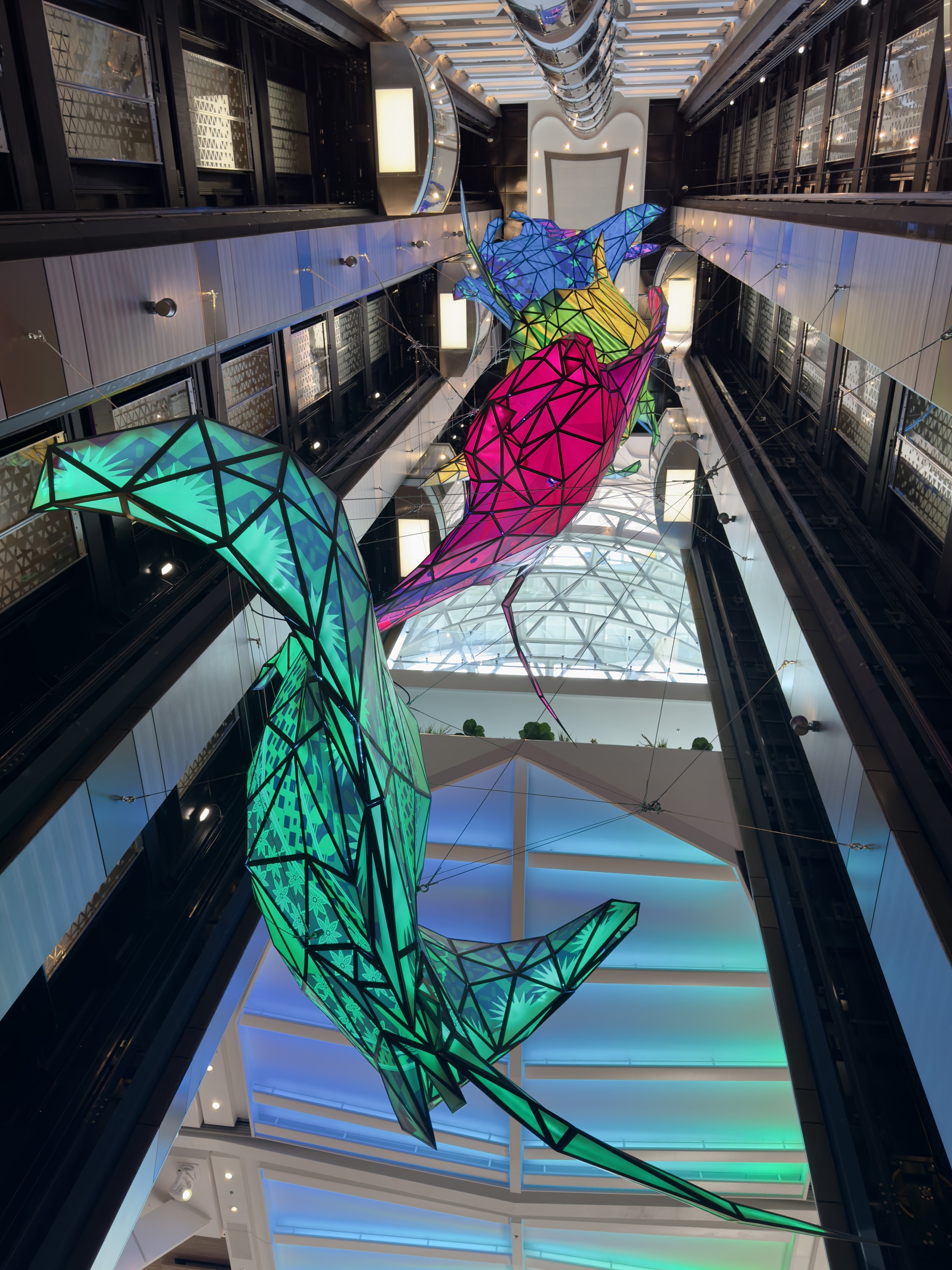 Colorful geometric fish sculptures hang in cruise ship atrium