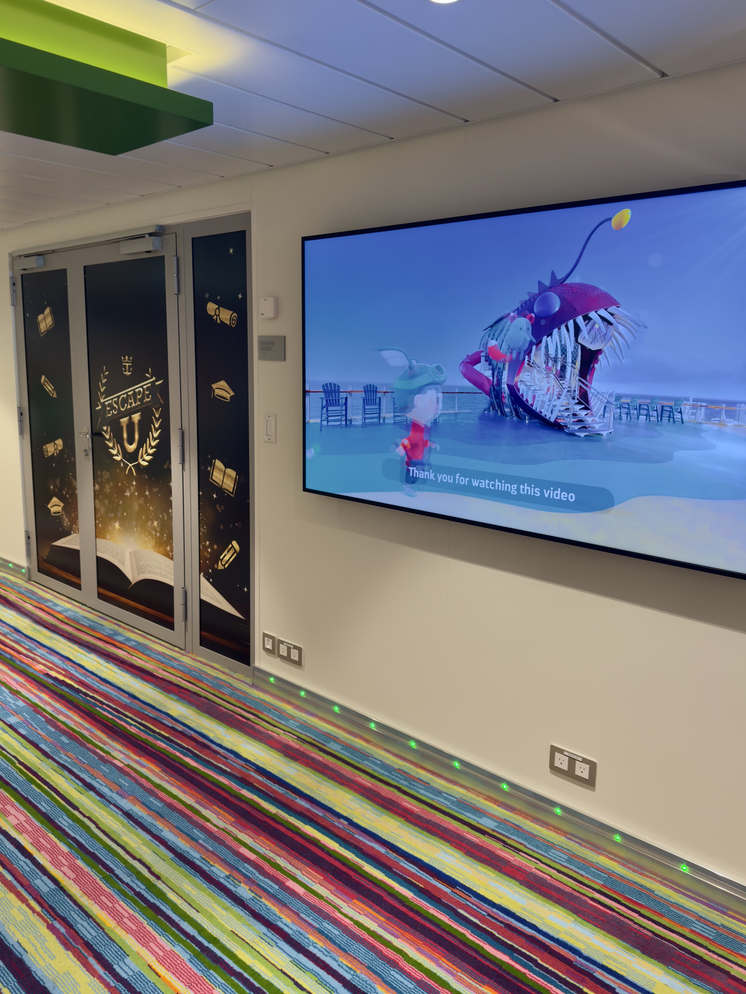 Modern cruise ship hallway with escape room and animated video display