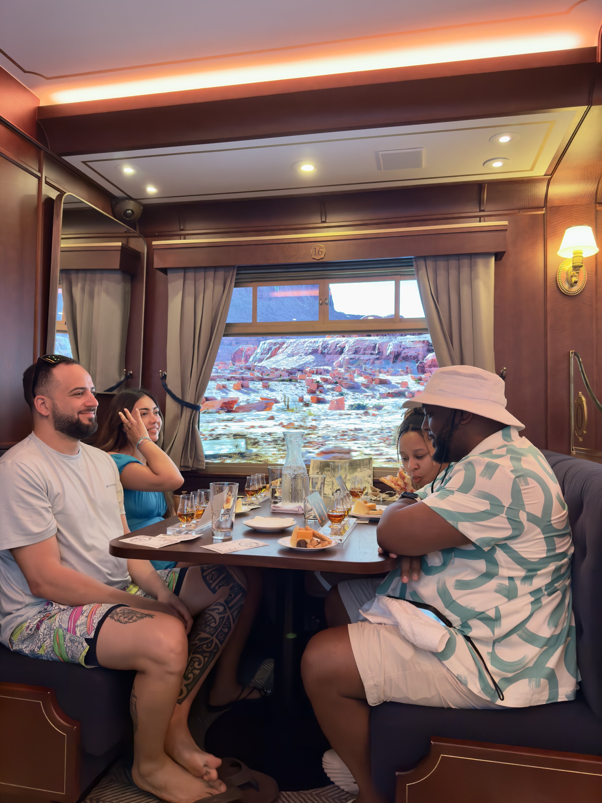 Four people dining in luxurious cruise ship cabin overlooking red rock canyon landscape