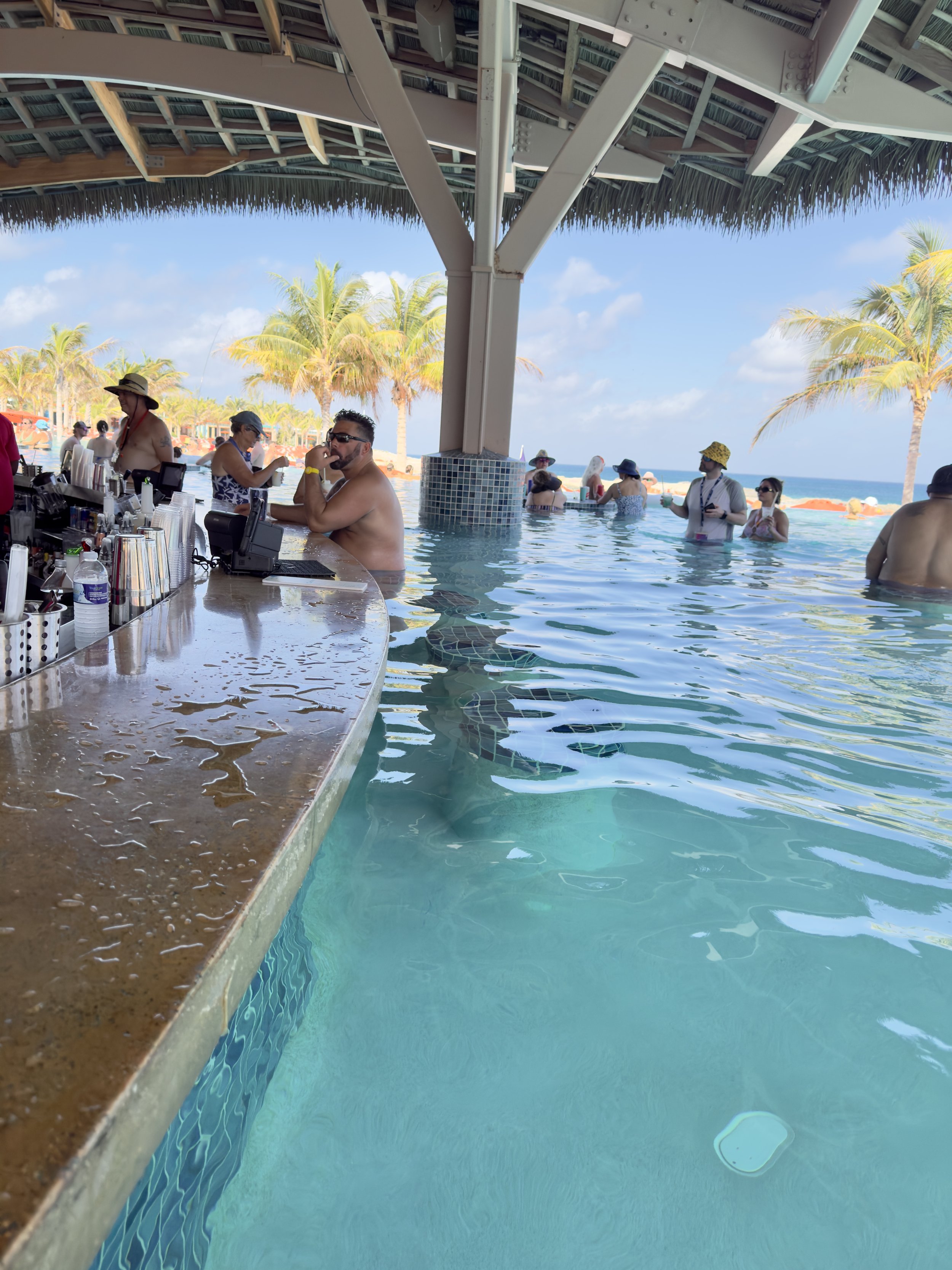 Beach bar and pool with tropical ocean view, passengers swimming