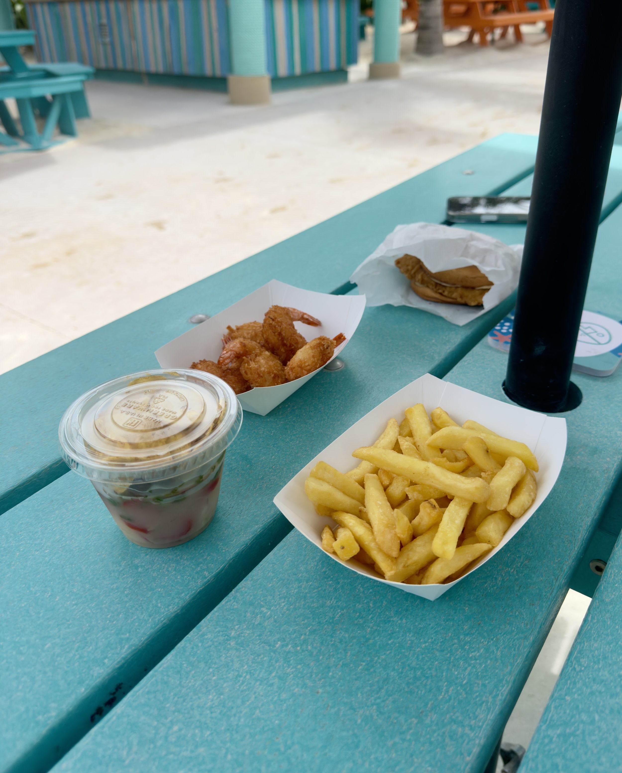 Fried shrimp, fries, and sauce on turquoise beach table