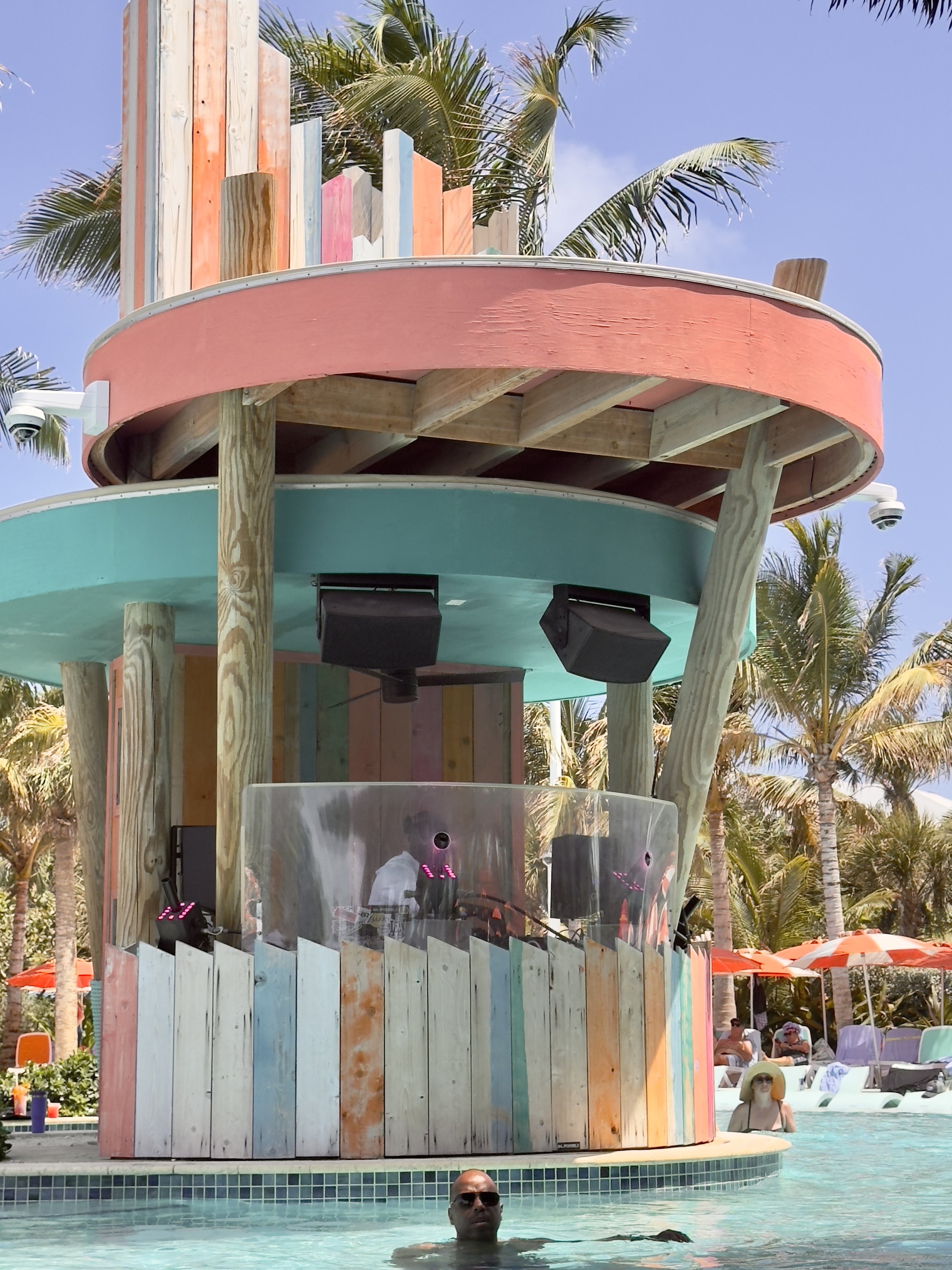 Colorful poolside bar structure with swimmers at tropical resort
