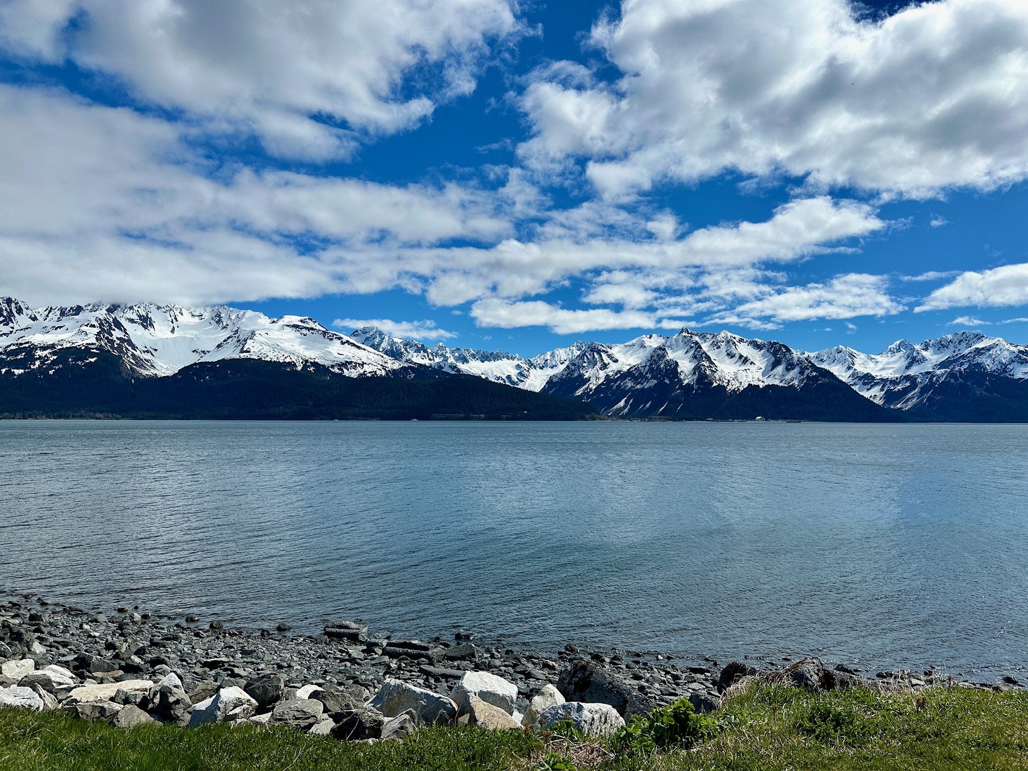 Snow-capped mountains overlooking calm turquoise glacial lake waters