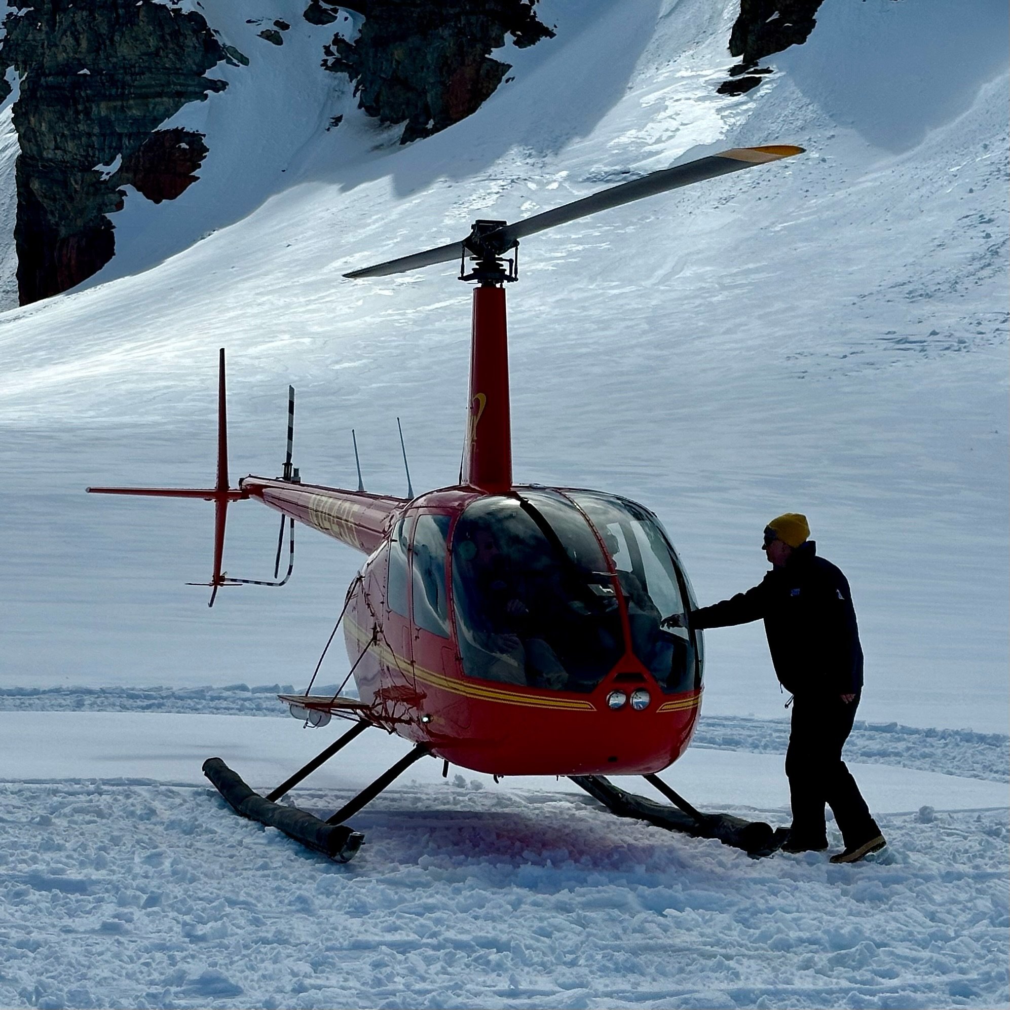 Red helicopter landed on snowy mountain glacier