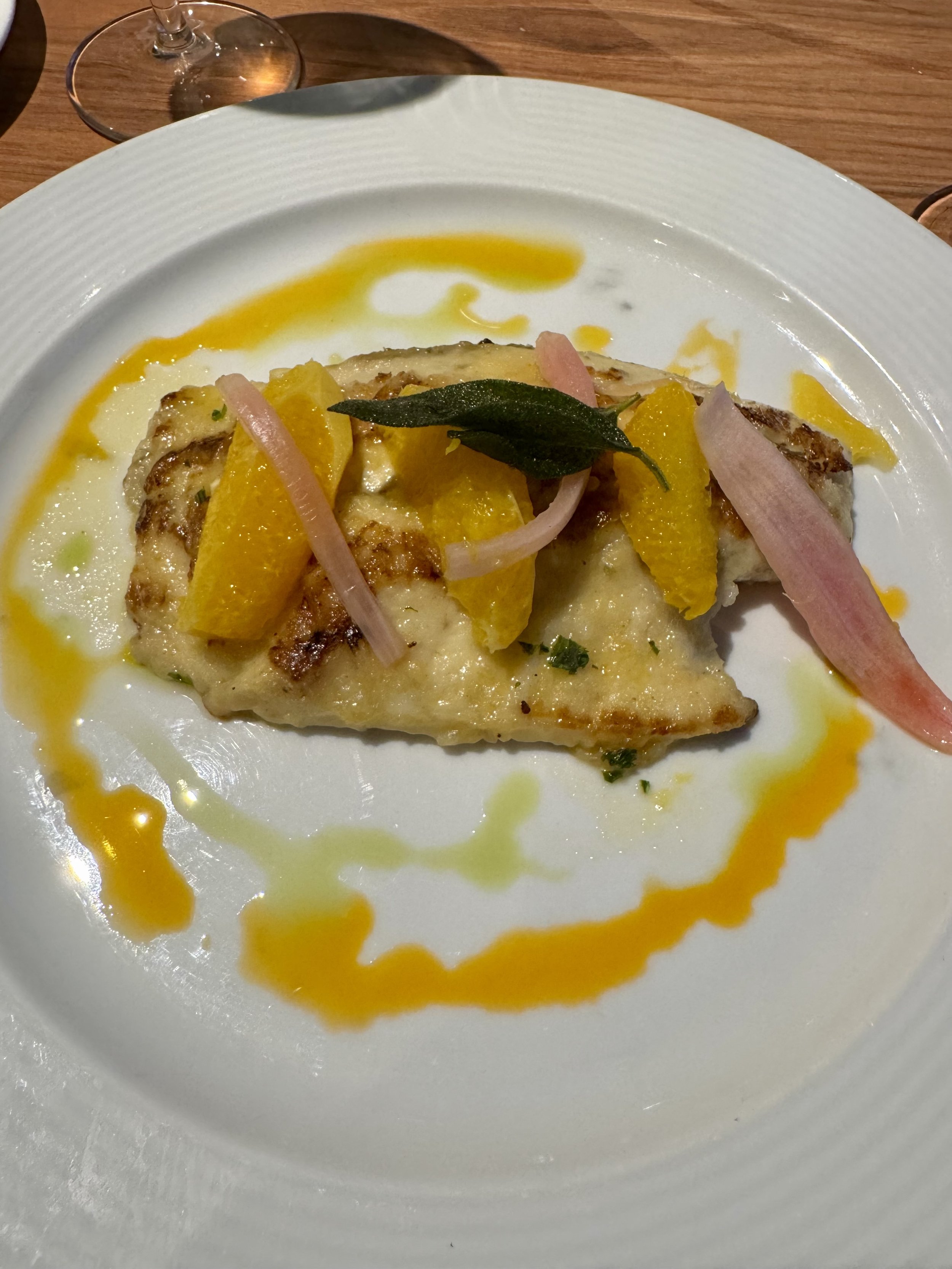 Pan-seared fish fillet with apple garnish and sage leaf