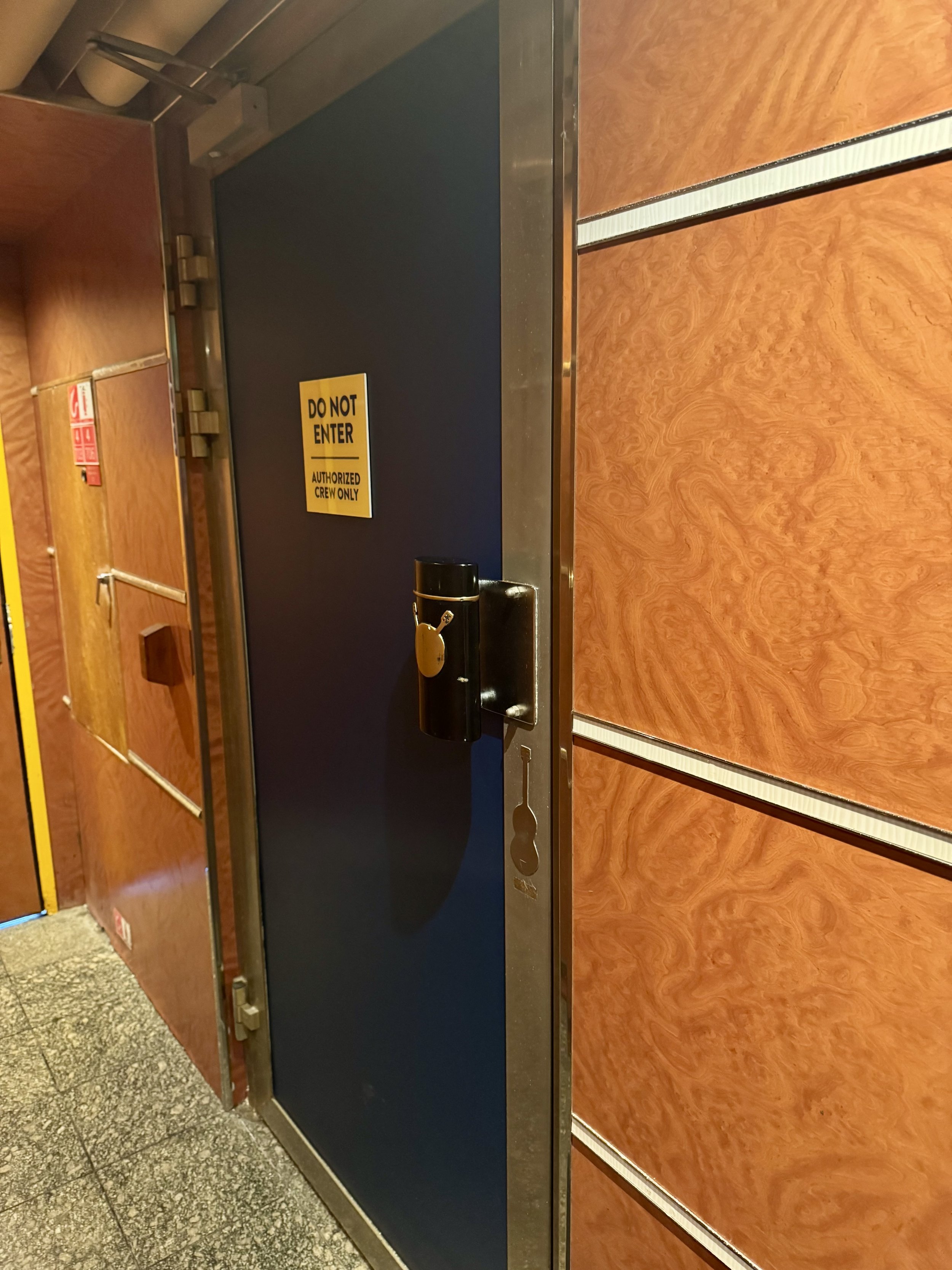 Restricted crew-only door with yellow warning sign on cruise ship