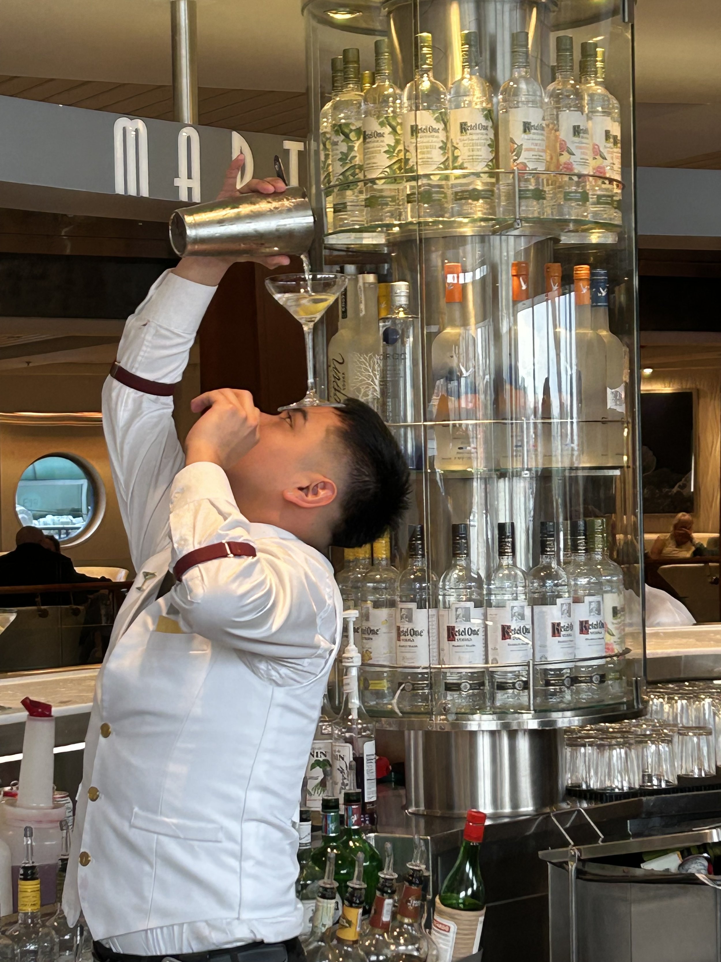 Bartender pouring cocktail from shaker at elegant cruise ship bar